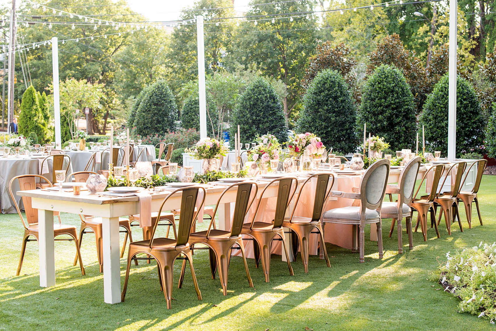 Mikkel Paige Photography pictures from a wedding at Merrimon-Wynne House in Raleigh, NC. Photo of the head dinner farm table with pink linen napkins, grey plates, marble chargers and copper chairs.