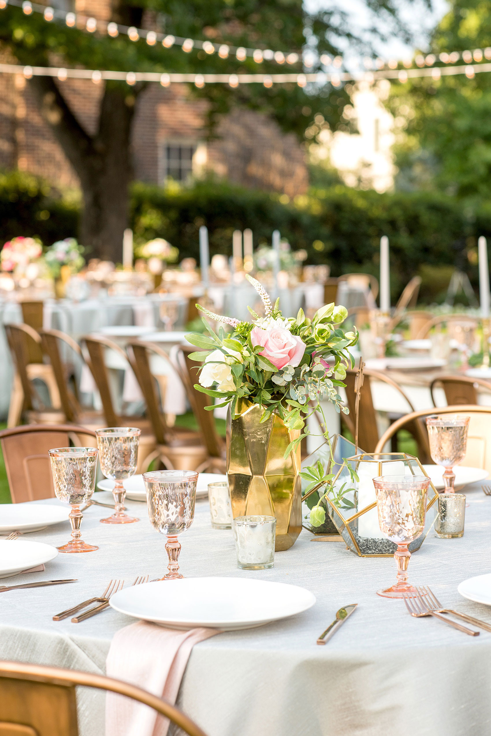 Mikkel Paige Photography pictures from a wedding at Merrimon-Wynne House in Raleigh, NC. Photo of the outdoor reception on the lawn, with round and rectangular farm tables, pink linen napkins, grey plates, and floral centerpieces.