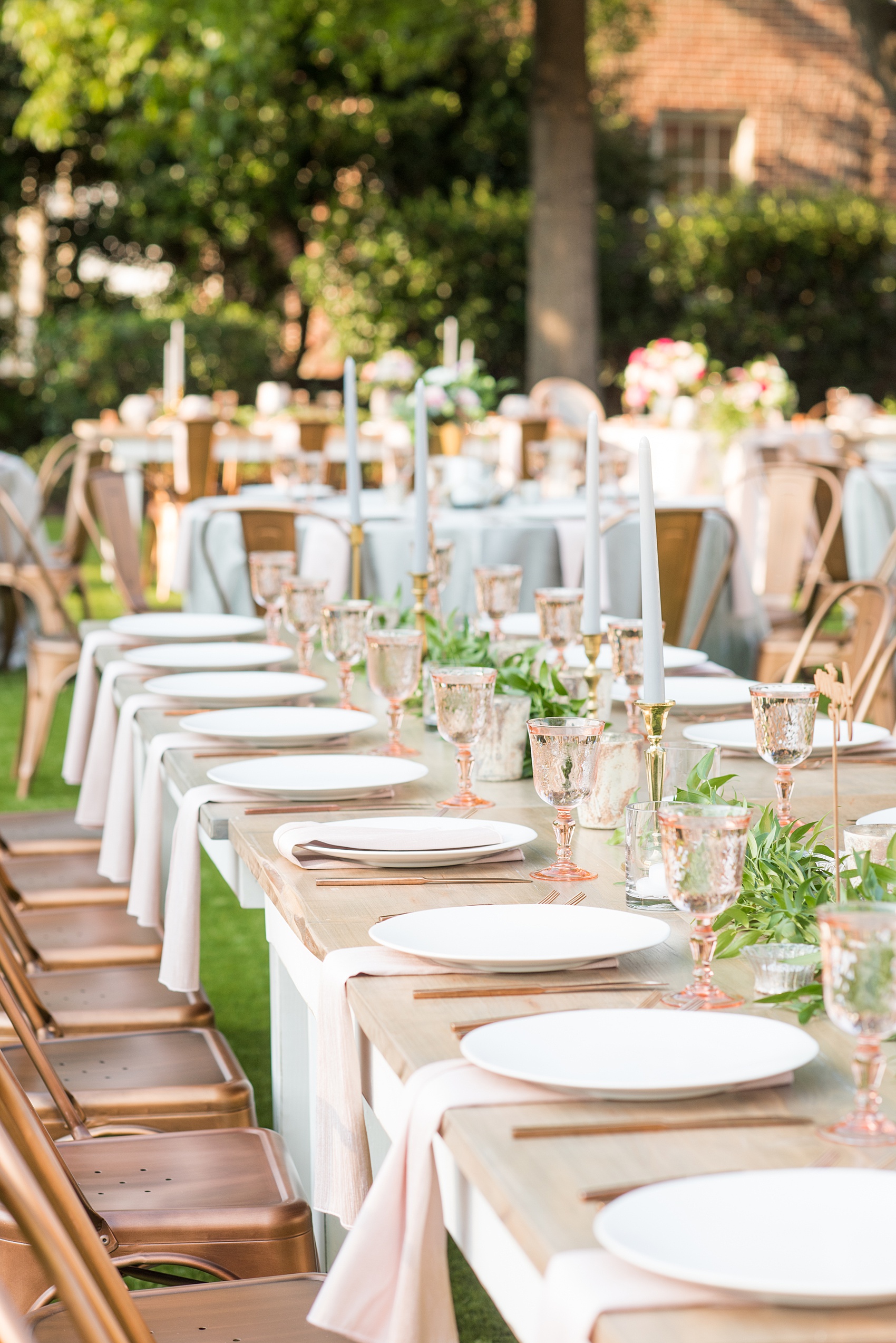 Mikkel Paige Photography pictures from a wedding at Merrimon-Wynne House in Raleigh, NC. Photo of the outdoor reception on the lawn, with round and rectangular farm tables, pink linen napkins, grey plates, and floral centerpieces.