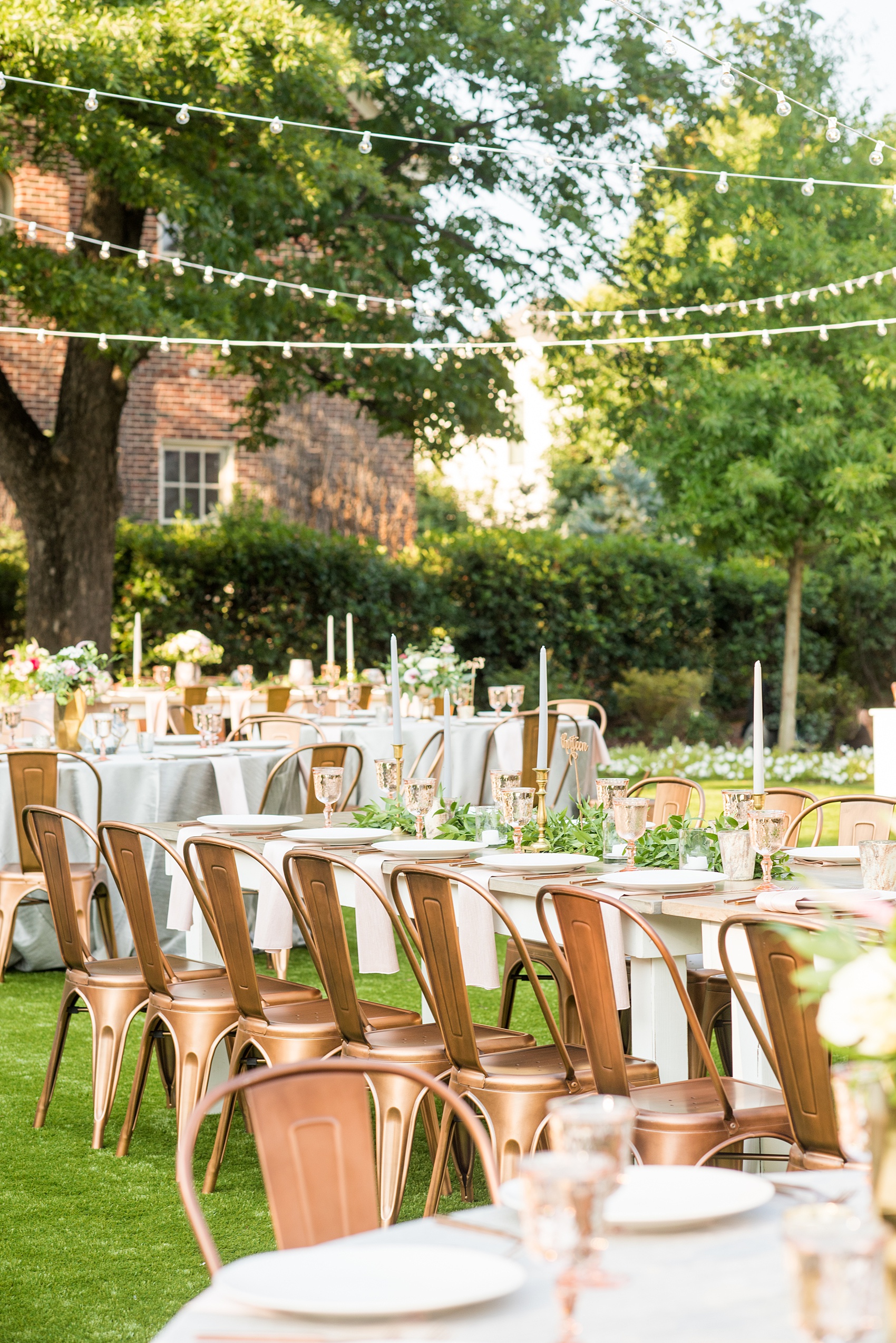 Mikkel Paige Photography pictures from a wedding at Merrimon-Wynne House in Raleigh, NC. Photo of the outdoor reception on the lawn, with round and farm tables, pink linen napkins, grey plates, and floral centerpieces.