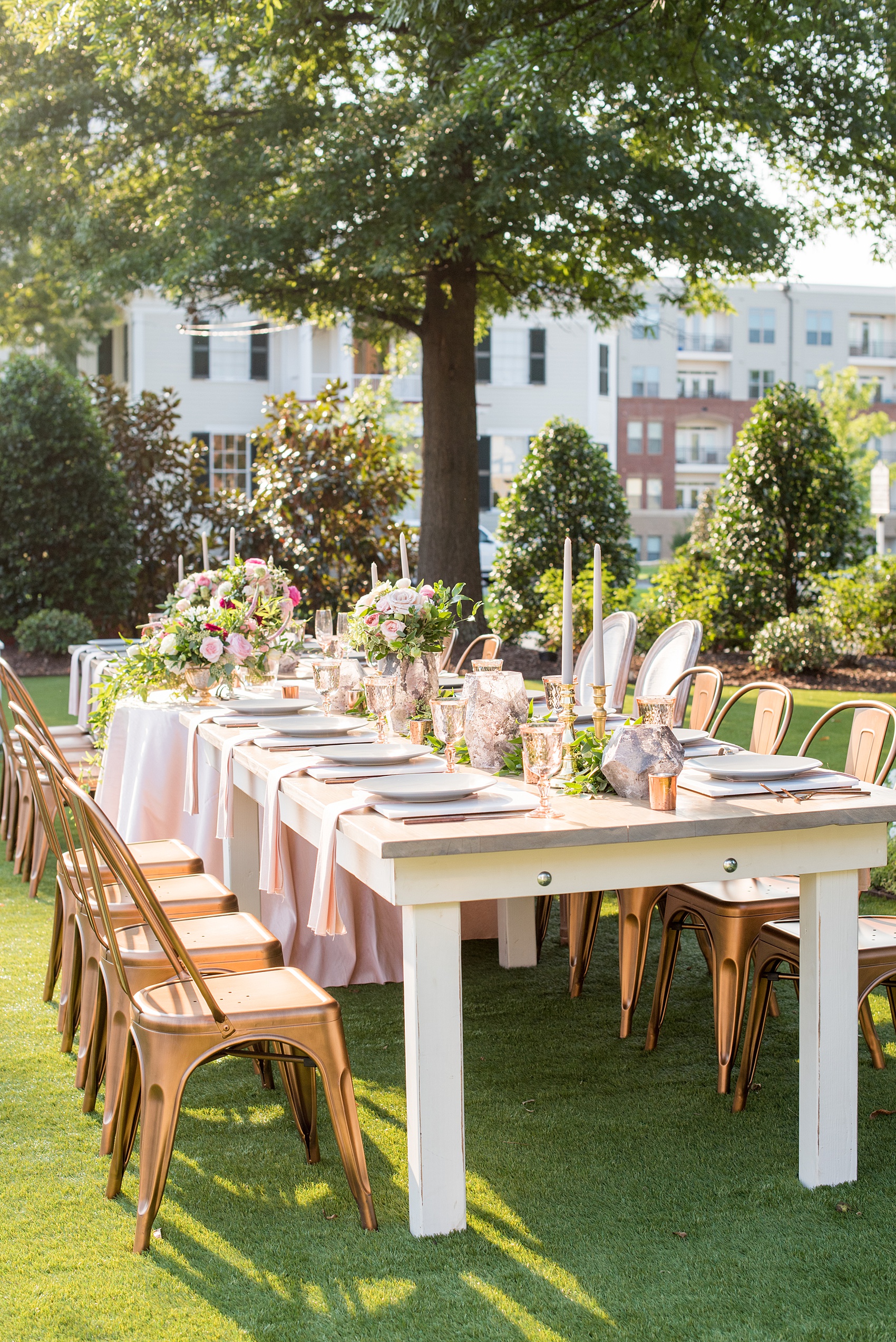 Mikkel Paige Photography pictures from a wedding at Merrimon-Wynne House in Raleigh, NC. Photo of the head dinner farm table with pink linen napkins, grey plates, marble chargers and copper chairs.