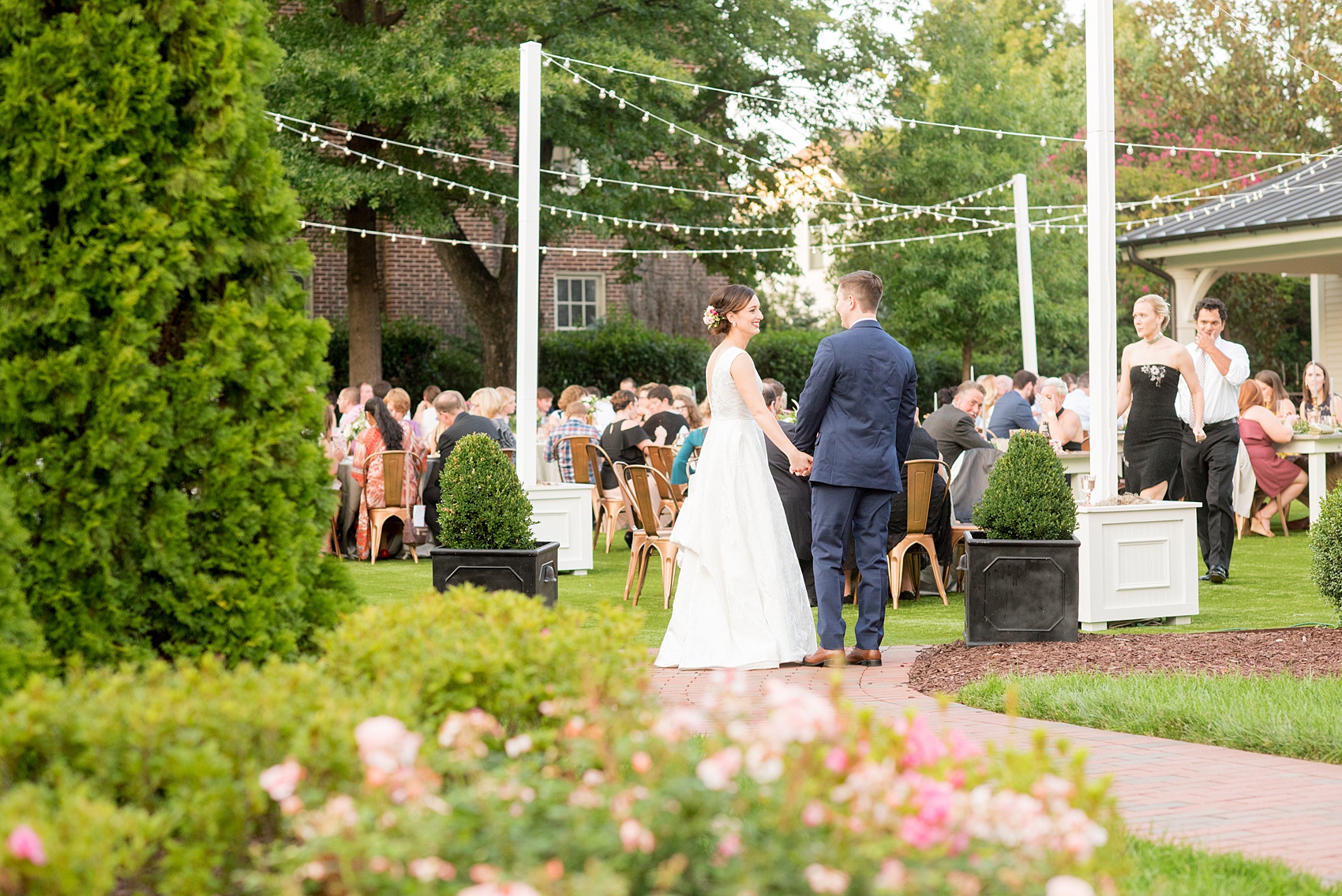 Mikkel Paige Photography pictures from a wedding at Merrimon-Wynne House in Raleigh, NC. Photo of the bride and groom joining their outdoor reception dinner.