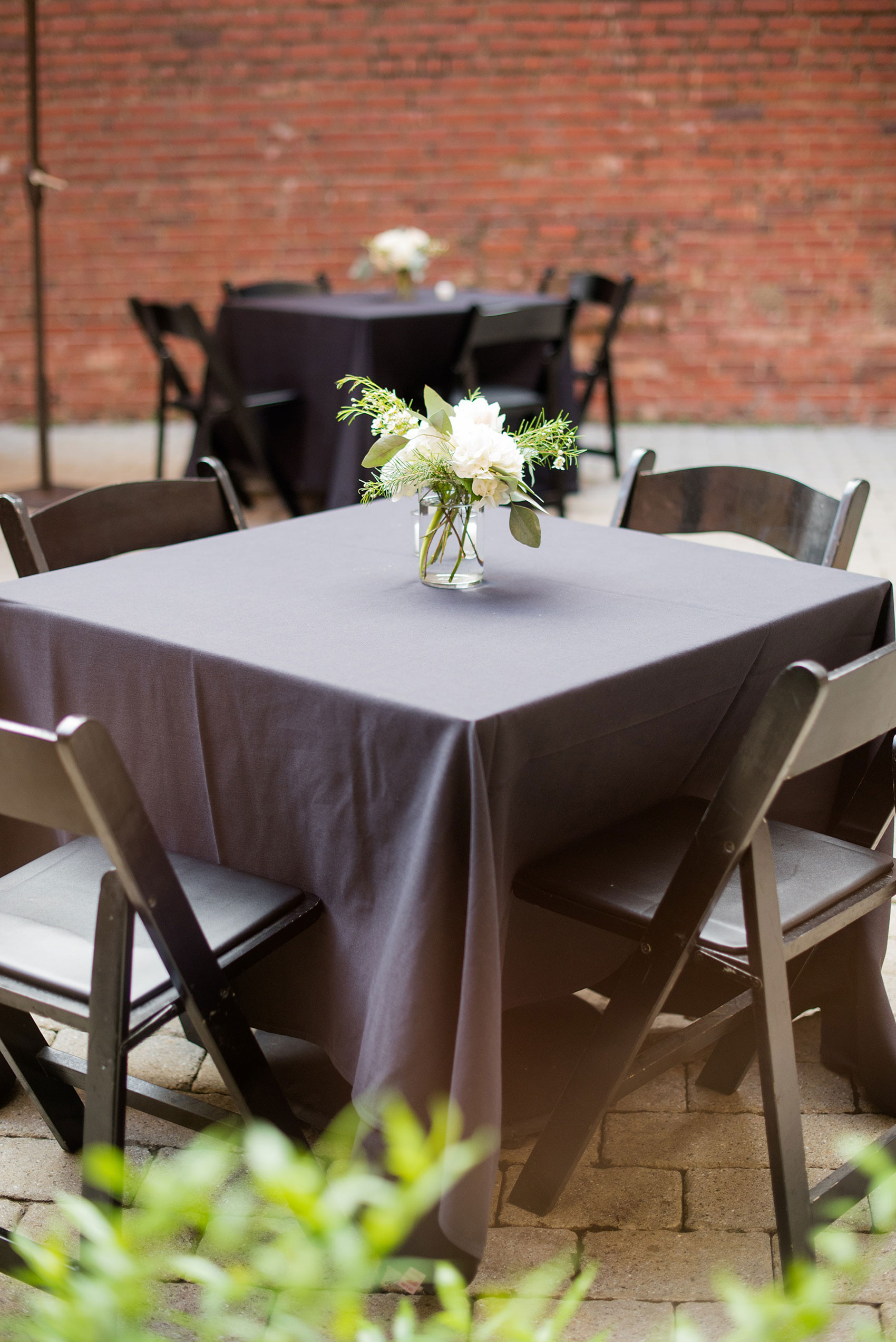 Mikkel Paige Photography photos from a downtown Raleigh wedding rehearsal dinner at Sitti restaurant. Picture of the tables with black tablecloths and white and green floral centerpieces.