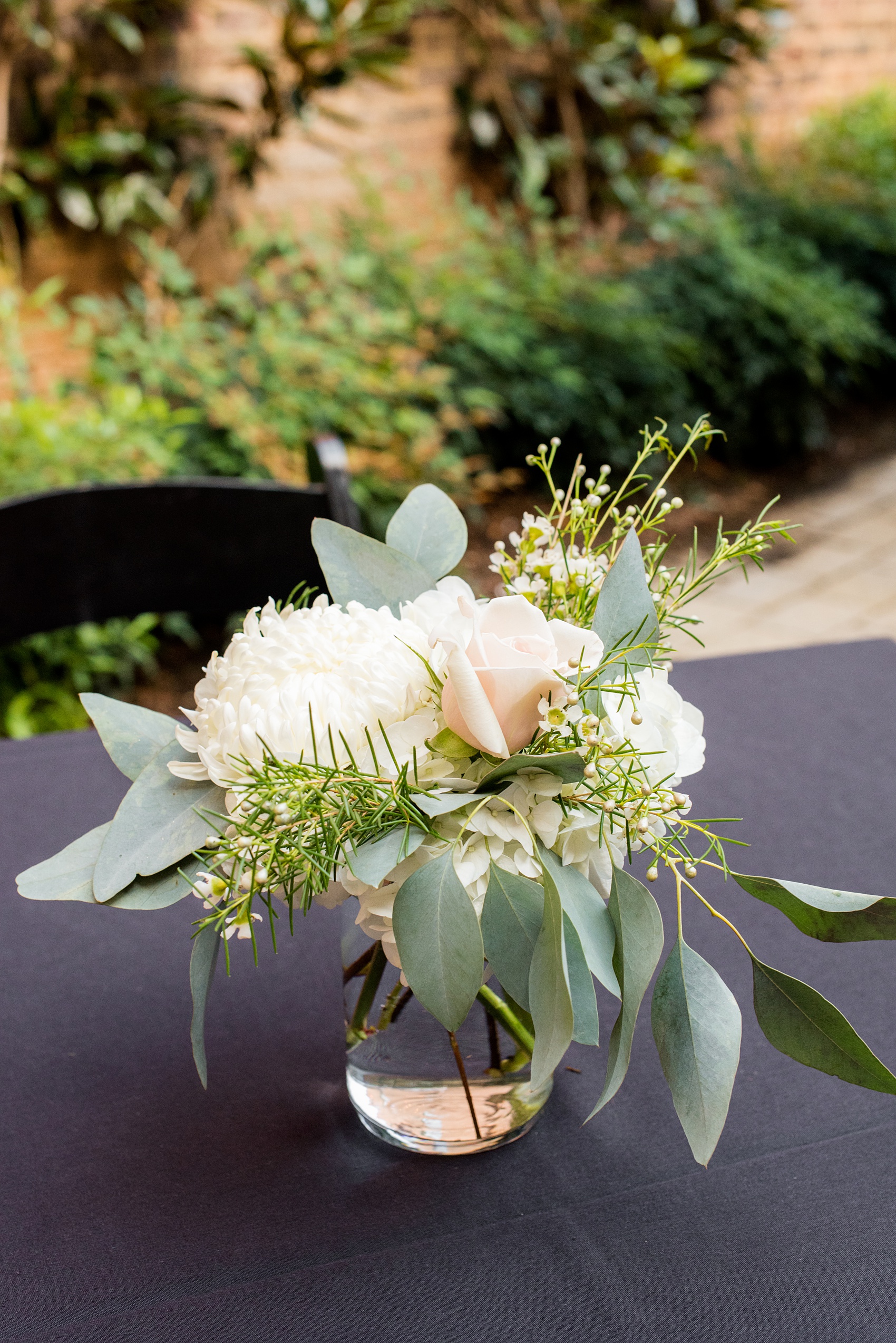 Mikkel Paige Photography photos from a downtown Raleigh wedding rehearsal dinner at Sitti restaurant. Picture of the tables with black tablecloths and white and green floral centerpieces.