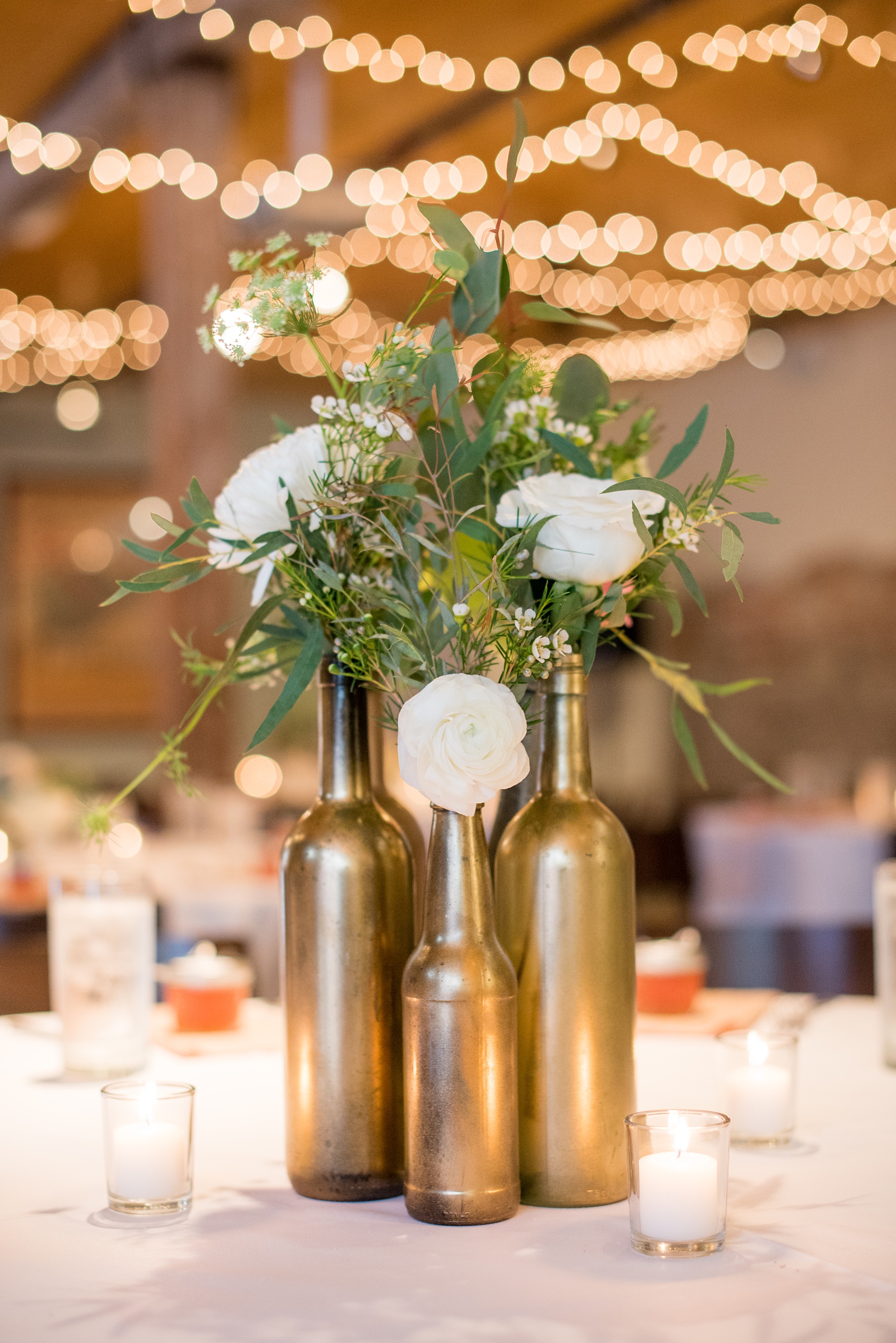 Mikkel Paige Photography photos from a downtown Raleigh wedding rehearsal dinner at Sitti restaurant. Photo of the floral centerpieces created with gold spray painted bottles, white flowers and greenery.