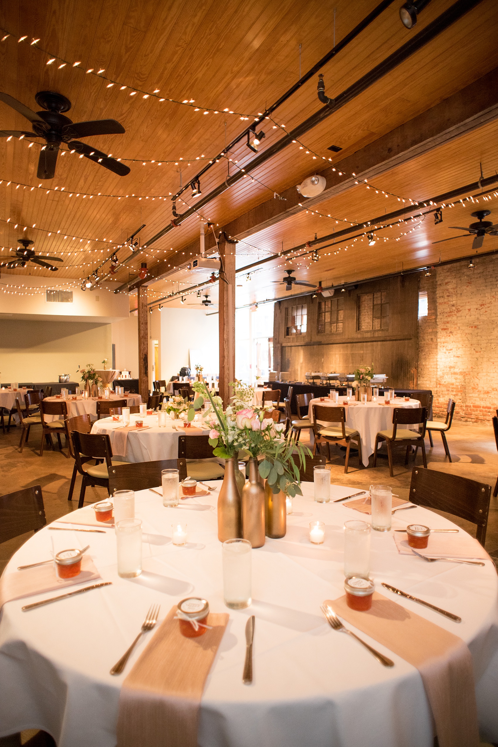 Mikkel Paige Photography photos from a downtown Raleigh wedding rehearsal dinner at Sitti restaurant. Photo of the inside seated dinner with candlelight, twinkle lights, floral centerpieces and jam guest favors.