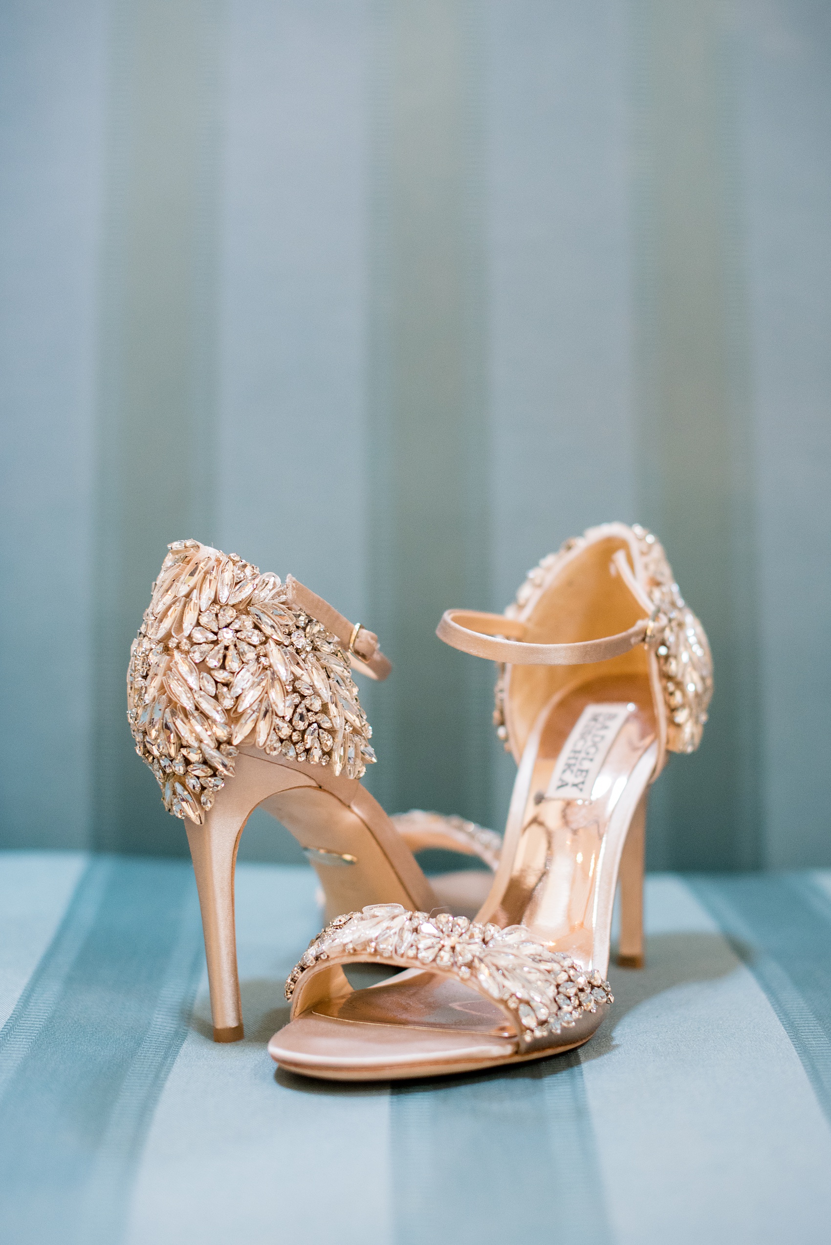 Mikkel Paige Photography photos from a wedding at Duke Chapel and Hope Valley Country Club in North Carolina. Detail photo of the bride's rhinestone gold Badgley Mischka heels against teal.