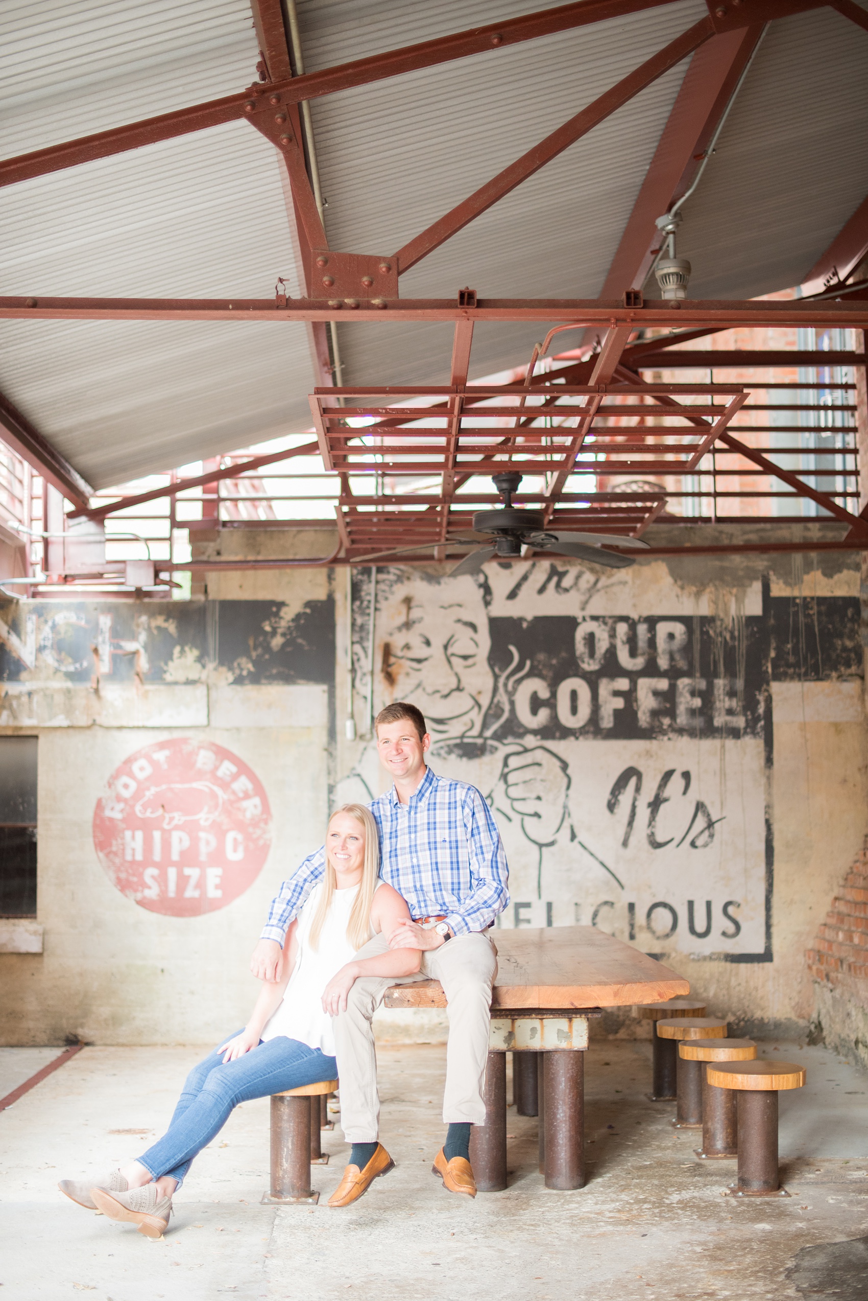 Mikkel Paige Photography photos from an engagement session at Durham's American Tobacco Campus in North Carolina. Picture of the couple near vintage signage.