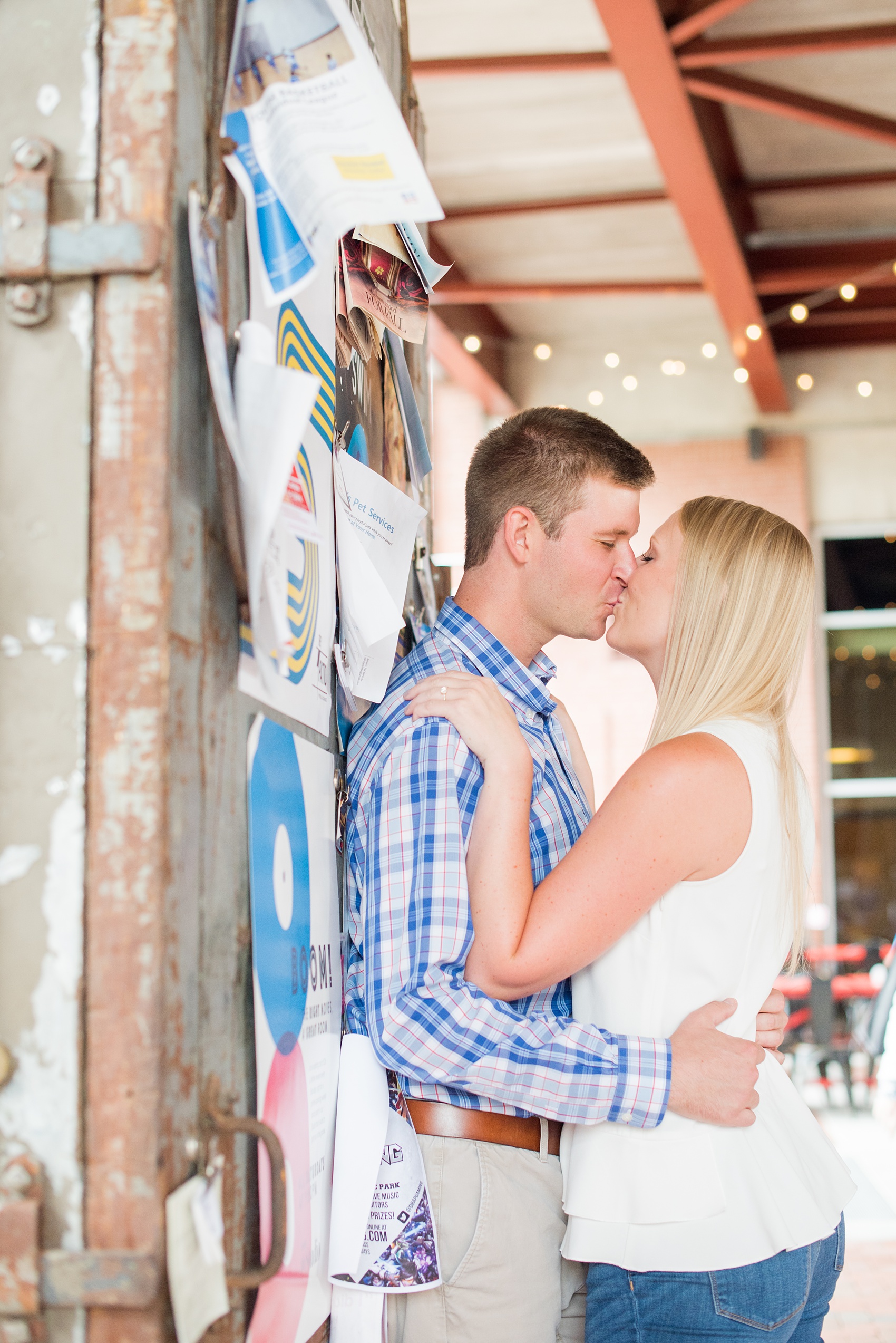 Mikkel Paige Photography photos from an engagement session at Durham's American Tobacco Campus in North Carolina. Picture of the couple near flyers.