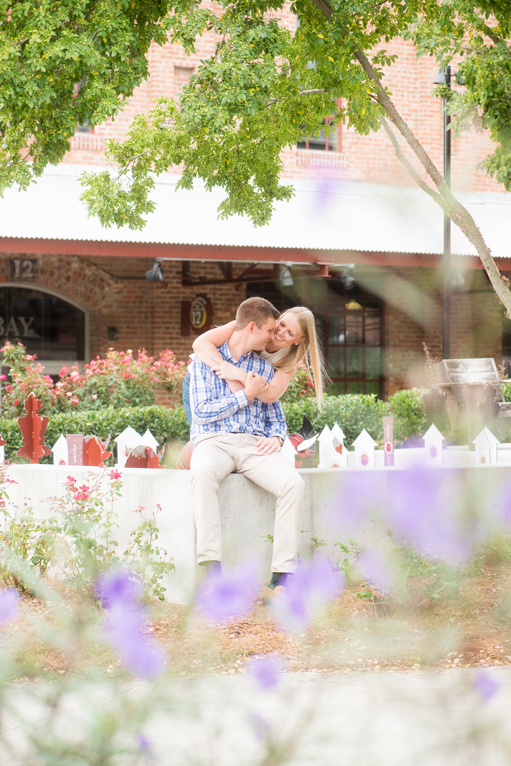 Mikkel Paige Photography photos from an engagement session at Durham's American Tobacco Campus in North Carolina. Picture of the couple through purple flowers.