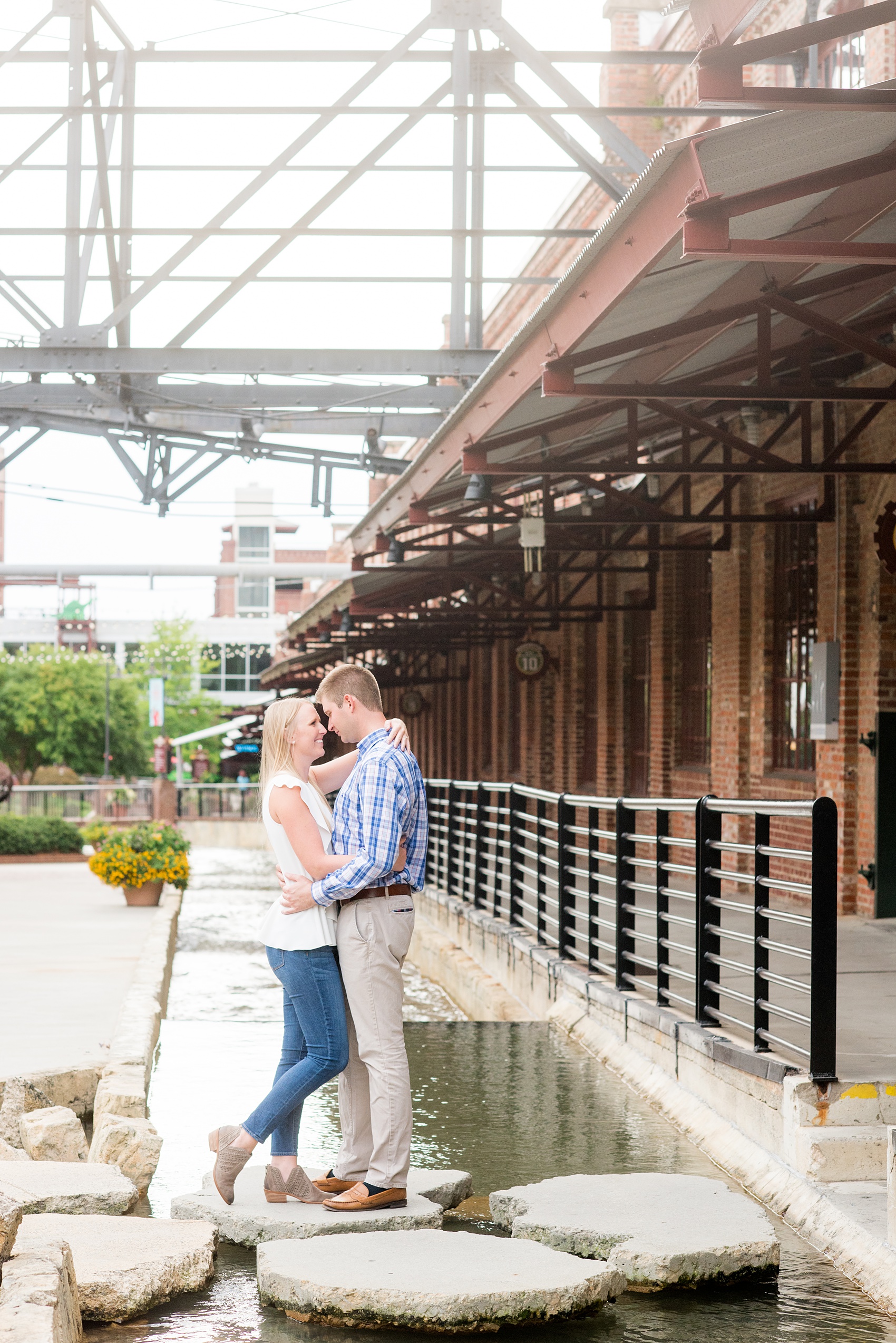 Mikkel Paige Photography photos from an engagement session at Durham's American Tobacco Campus in North Carolina. Picture of the couple standing on rocks in a water feature.