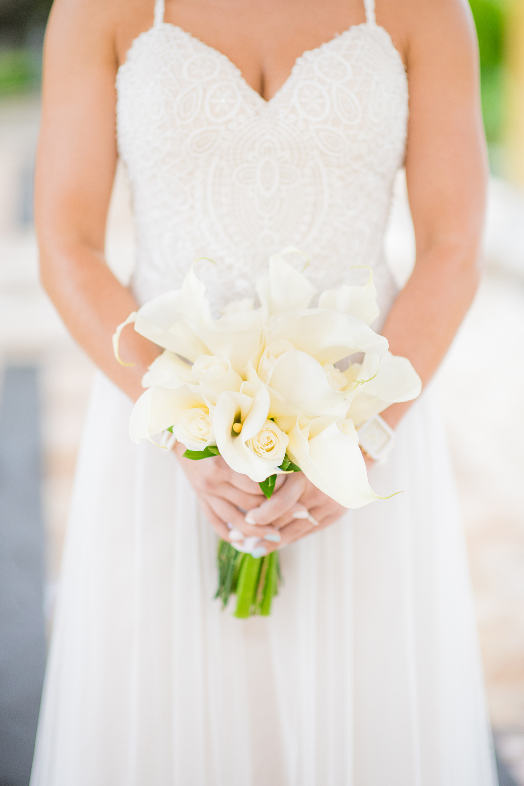 Mikkel Paige Photography photos from a wedding at Grand Paraiso, Mexico, Playa del Carmen Iberostar resort. Picture of the bride holding her calla lily and rose white bouquet. 