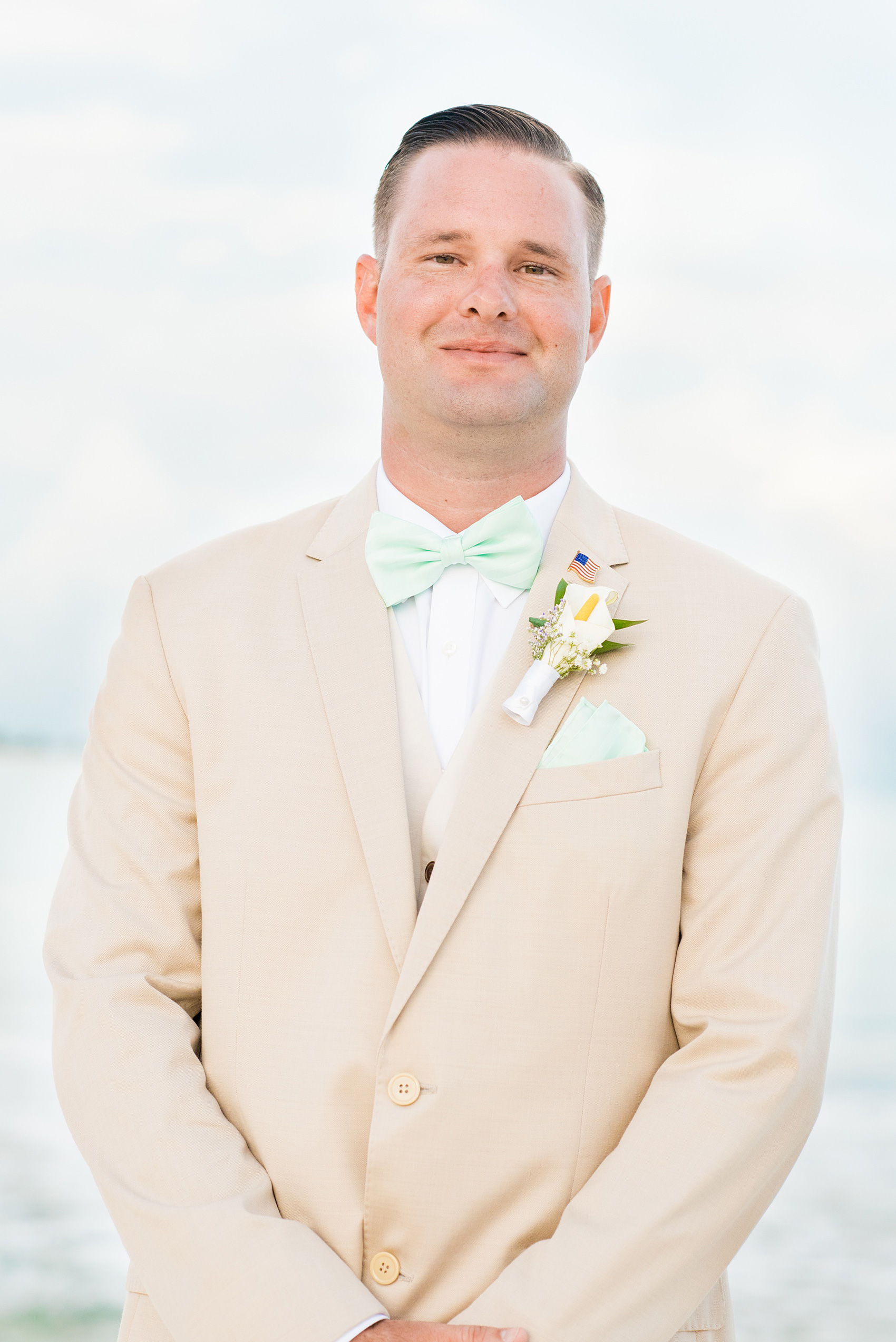 Mikkel Paige Photography photos from a wedding at Grand Paraiso, Mexico, Playa del Carmen Iberostar resort. Picture of the groom in a tan suit and light mint green bow tie.