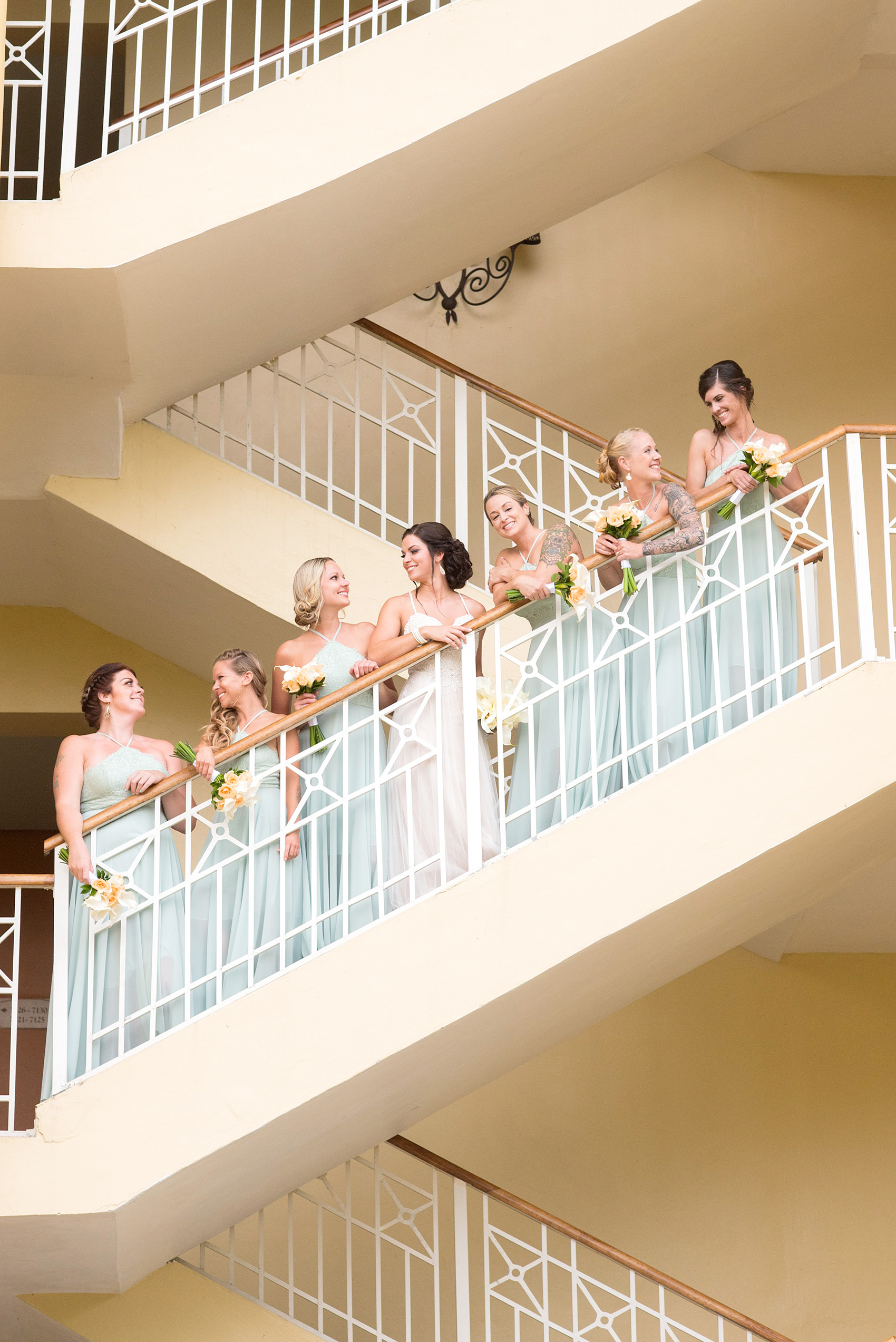 Mikkel Paige Photography photos from a wedding at Grand Paraiso, Mexico, Playa del Carmen Iberostar resort. Picture of the bride and her bridesmaids on the stairs of the resort. The bridesmaids wore mint green gowns.