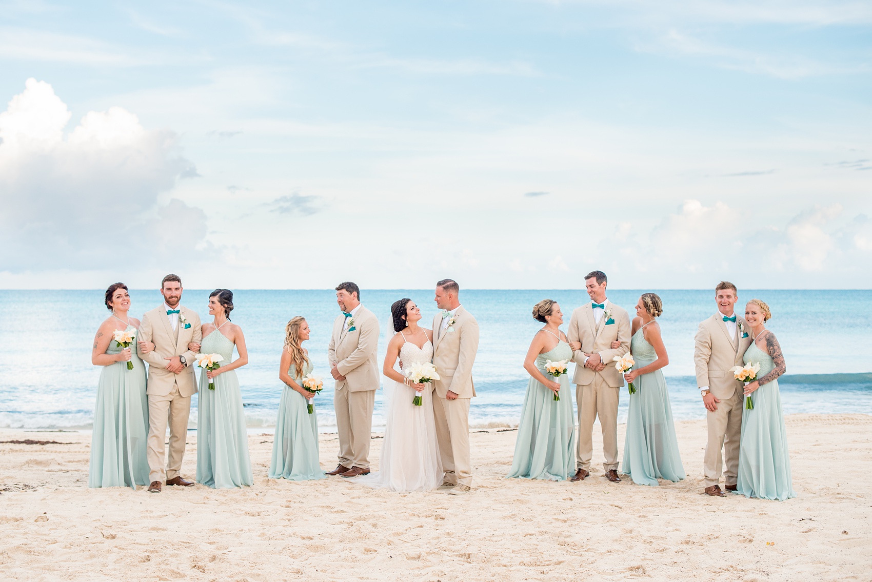 Mikkel Paige Photography photos from a wedding at Grand Paraiso, Mexico, Playa del Carmen Iberostar resort. Picture of the bridal party in mint green gowns and groomsmen in tan suits on the beach.