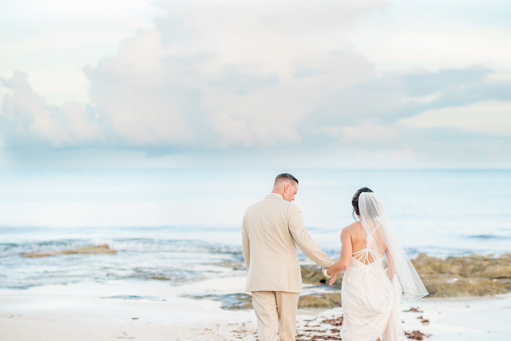 Mikkel Paige Photography photos from a wedding at Grand Paraiso, Mexico, Playa del Carmen Iberostar resort. Picture of the bride and groom walking to on the beach.