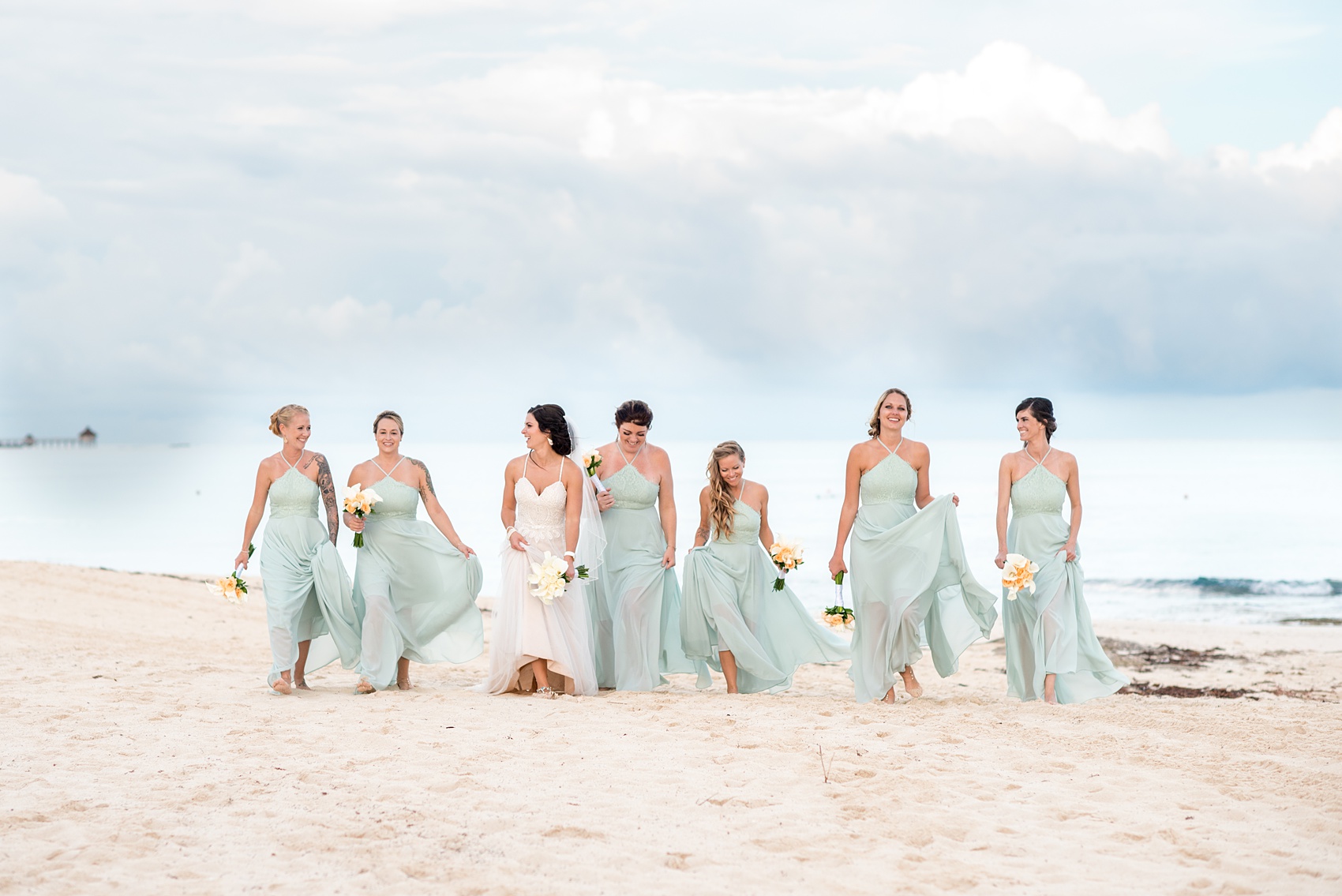 Mikkel Paige Photography photos from a wedding at Grand Paraiso, Mexico, Playa del Carmen Iberostar resort. Picture of the bride and her bridesmaids walking on the beach. The bridesmaids wore mint green gowns.