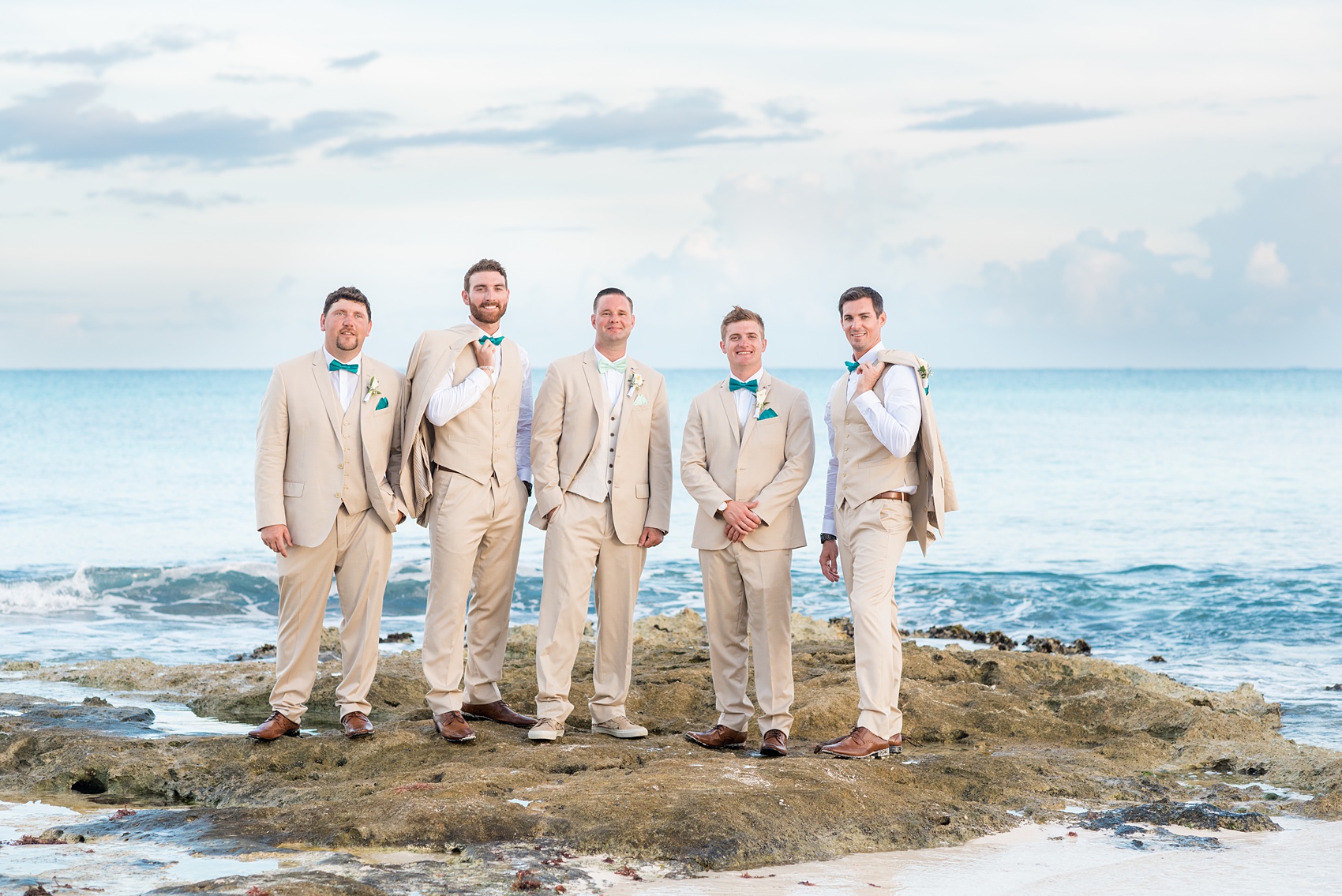 Mikkel Paige Photography photos from a wedding at Grand Paraiso, Mexico, Playa del Carmen Iberostar resort. Picture of the groomsmen on the beach in tan suits and teal bow ties.