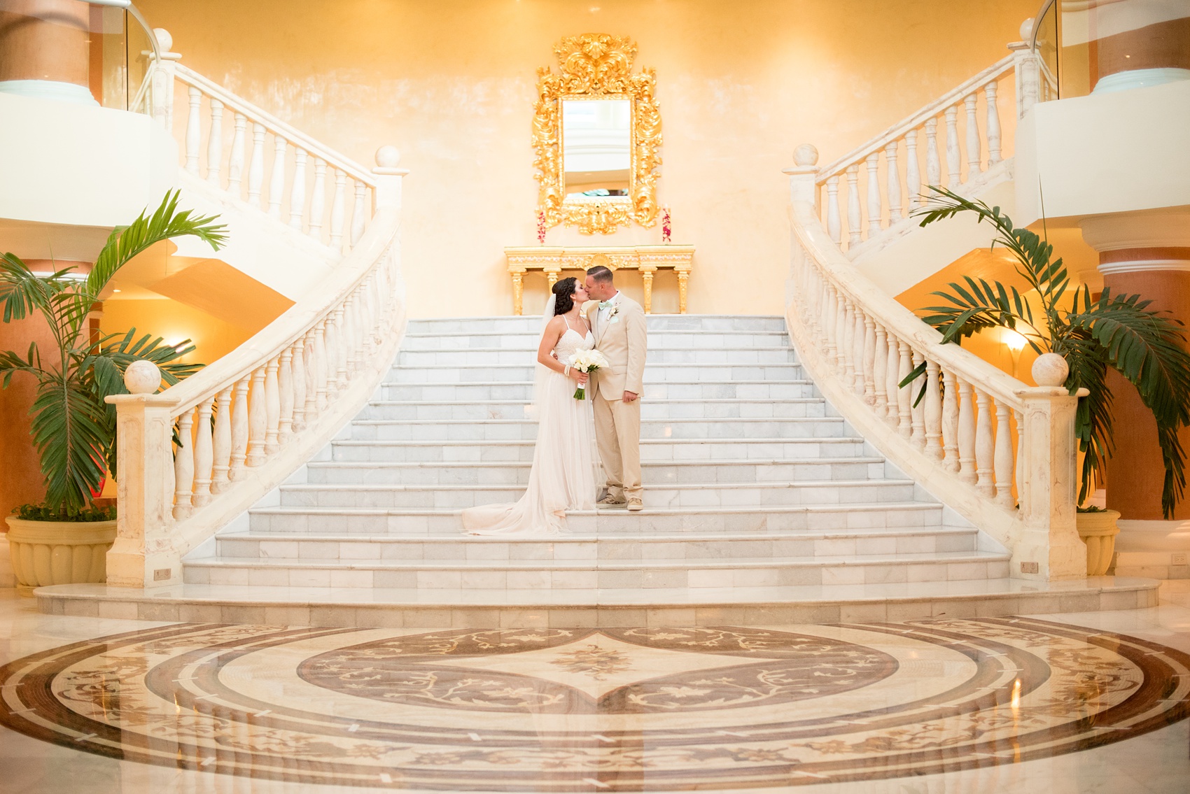 Mikkel Paige Photography photos from a wedding at Grand Paraiso, Mexico, Playa del Carmen Iberostar resort. Picture of the bride and groom kissing on the grand marble staircase in the resort.