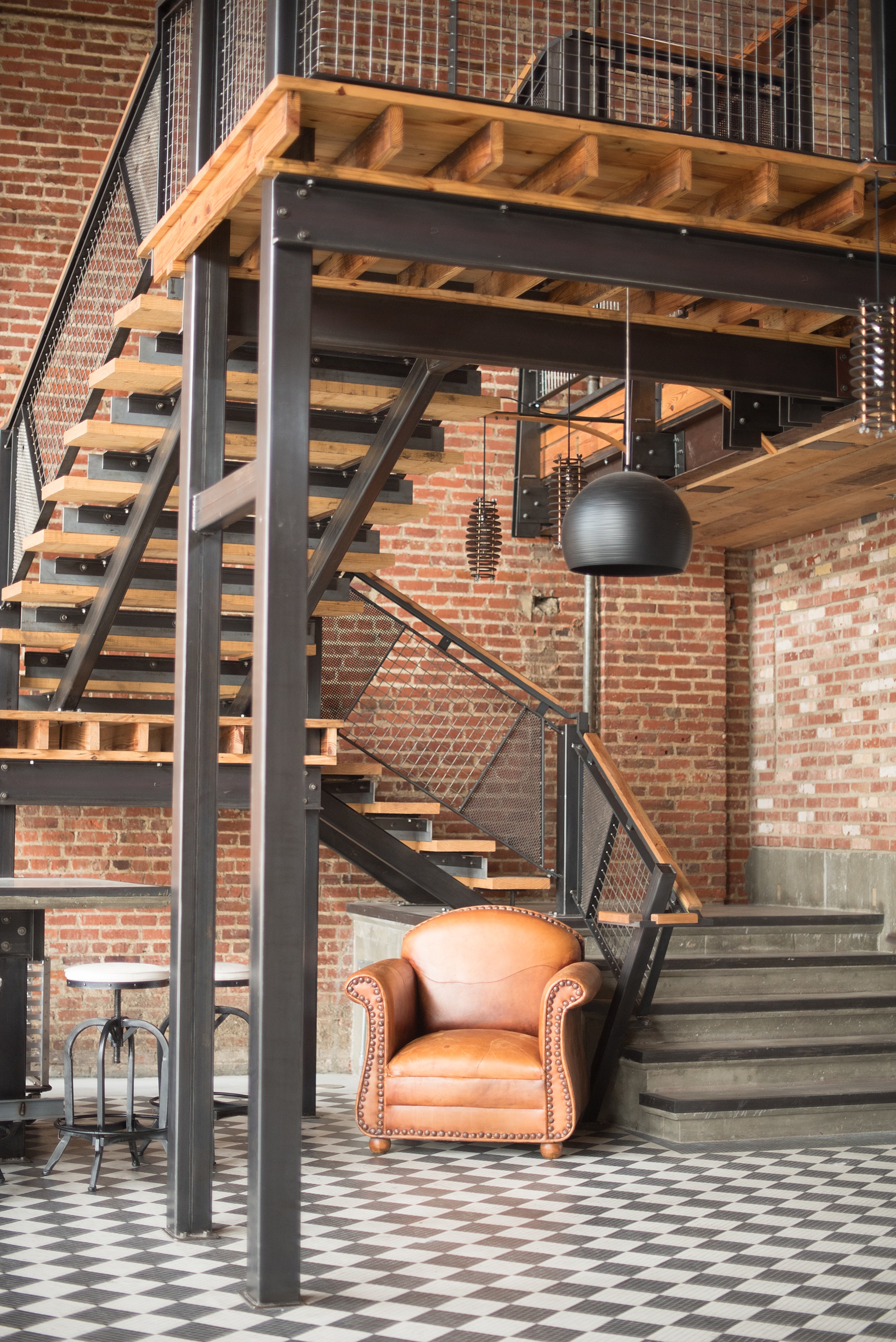 Mikkel Paige Photography pictures of Cadillac Service Garage venue in Greensboro, North Carolina. Photo of the interior bar cocktail hour with rustic masculine details and iron staircase.