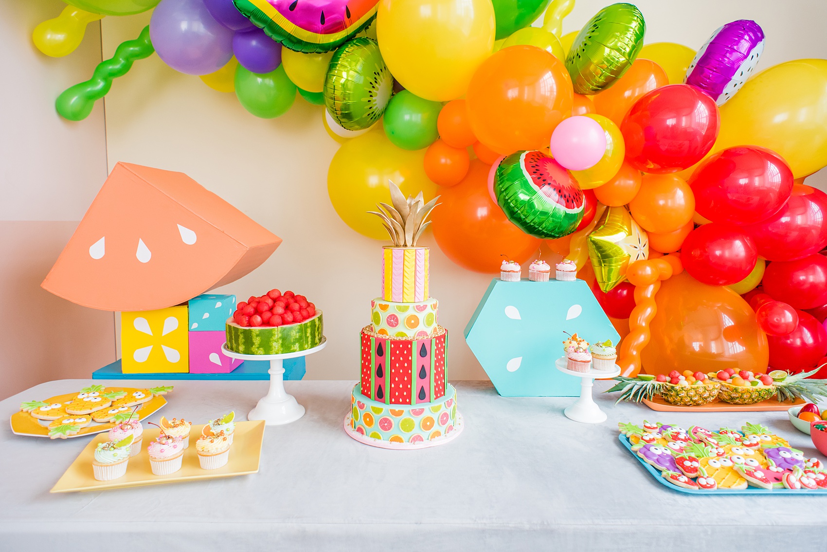 Mikkel Paige Photography photos of a Tutti Frutti theme birthday party. Featured on Martha Stewart. Picture of a dessert table with cake by Sugar Monster, cookies by Sweet Dani B and balloon and shapes by Michelle Bablo. Coordination by Color Pop Events.