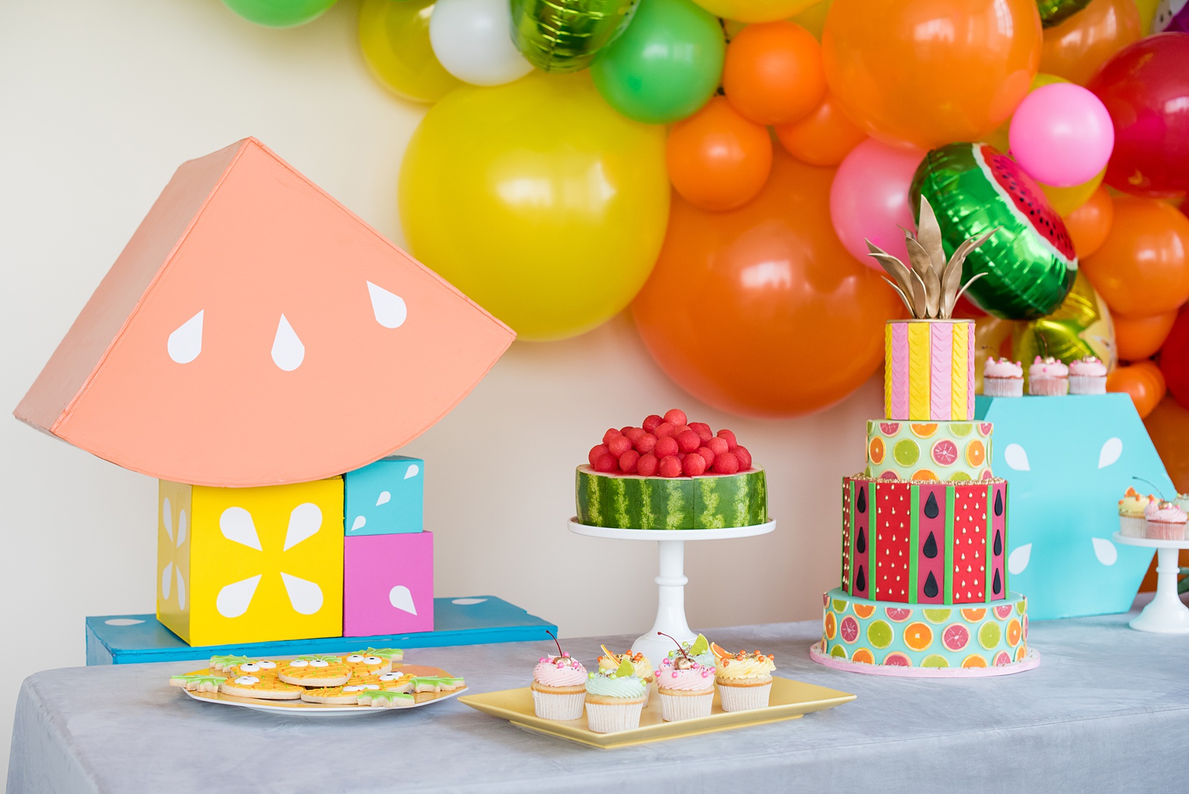 Mikkel Paige Photography photos of a Tutti Frutti theme birthday party. Featured on Martha Stewart. Picture of a dessert table with cake by Sugar Monster, cookies by Sweet Dani B and balloon and shapes by Michelle Bablo. Coordination by Color Pop Events.