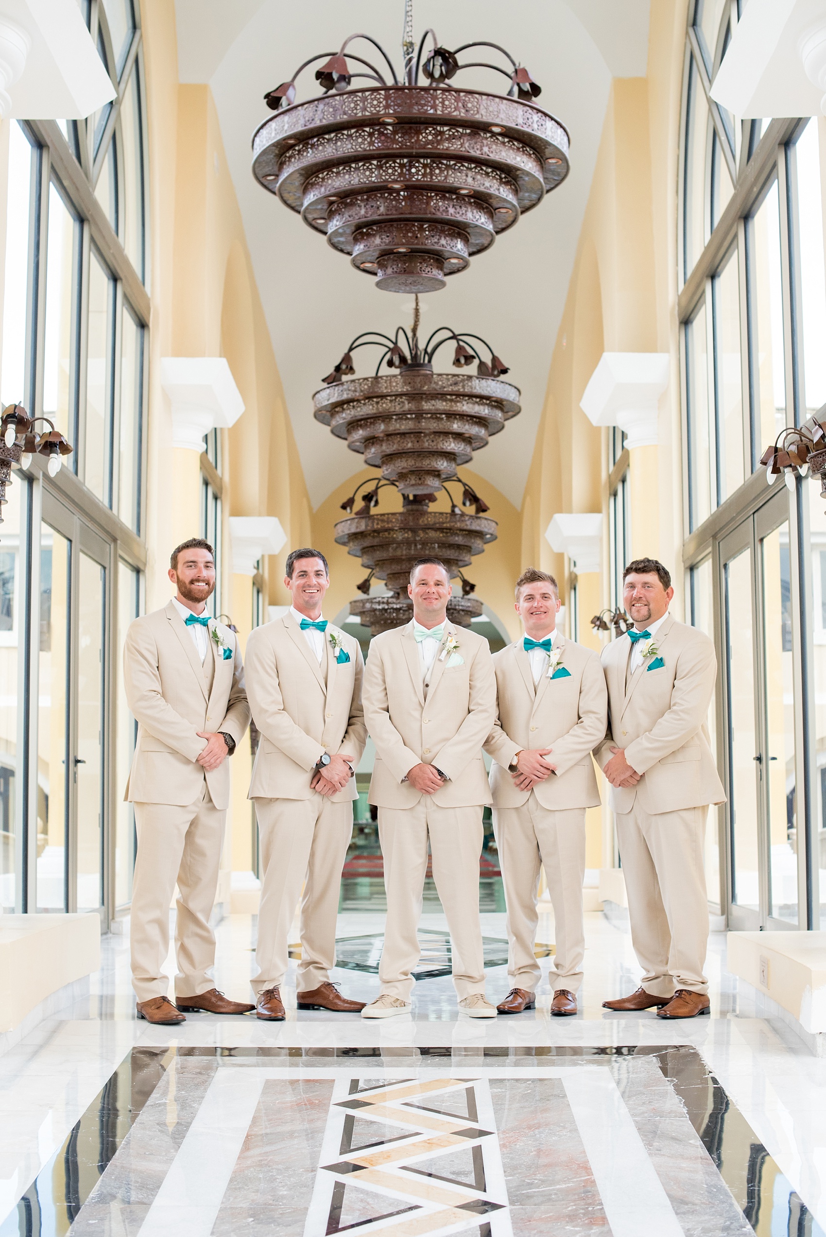 Mikkel Paige Photography photos from a wedding at Grand Paraiso, Mexico, Playa del Carmen Iberostar resort. Picture of the groom and his groomsmen in a grand hallway of the resort.
