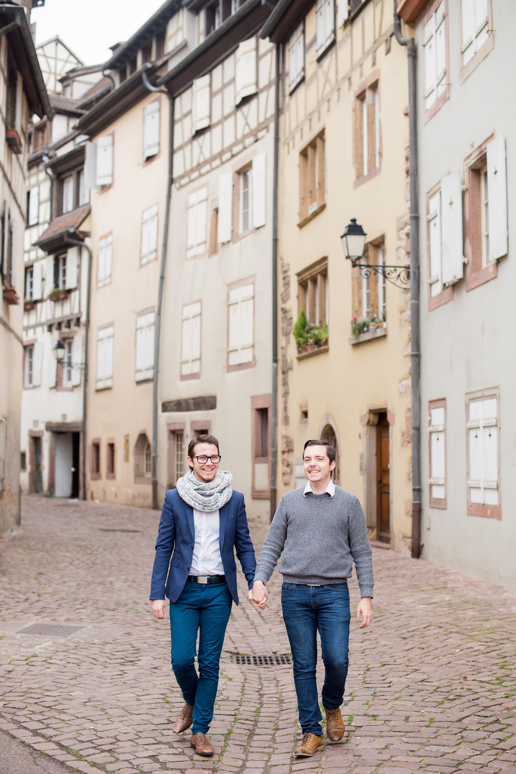 Mikkel Paige Photography pictures of an engagement session in Colmar, France in the Alsace region. Photo of the same sex couple walking through the cobblestone streets of the historic village.