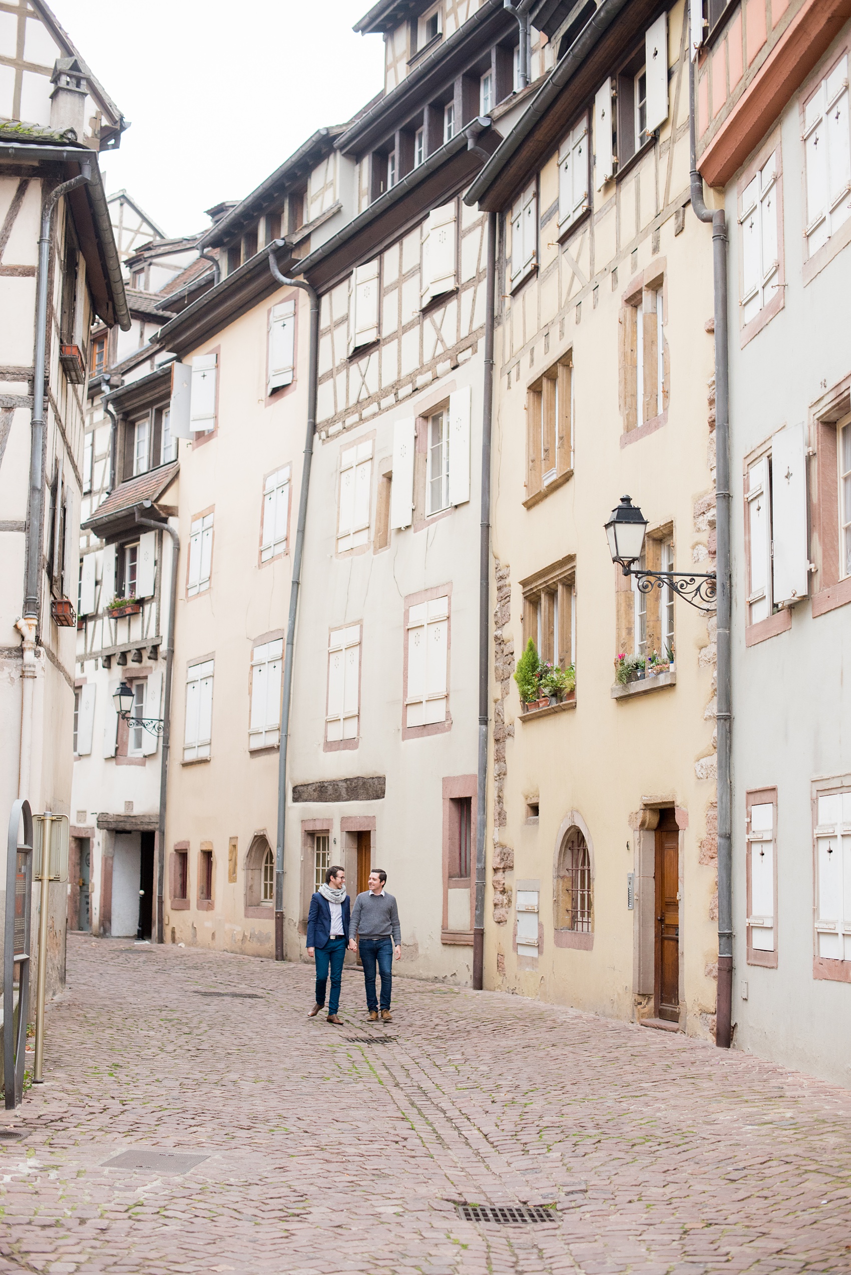 Mikkel Paige Photography pictures of an engagement session in Colmar, France in the Alsace region. Photo of the same sex couple walking through the cobblestone streets of the historic village.