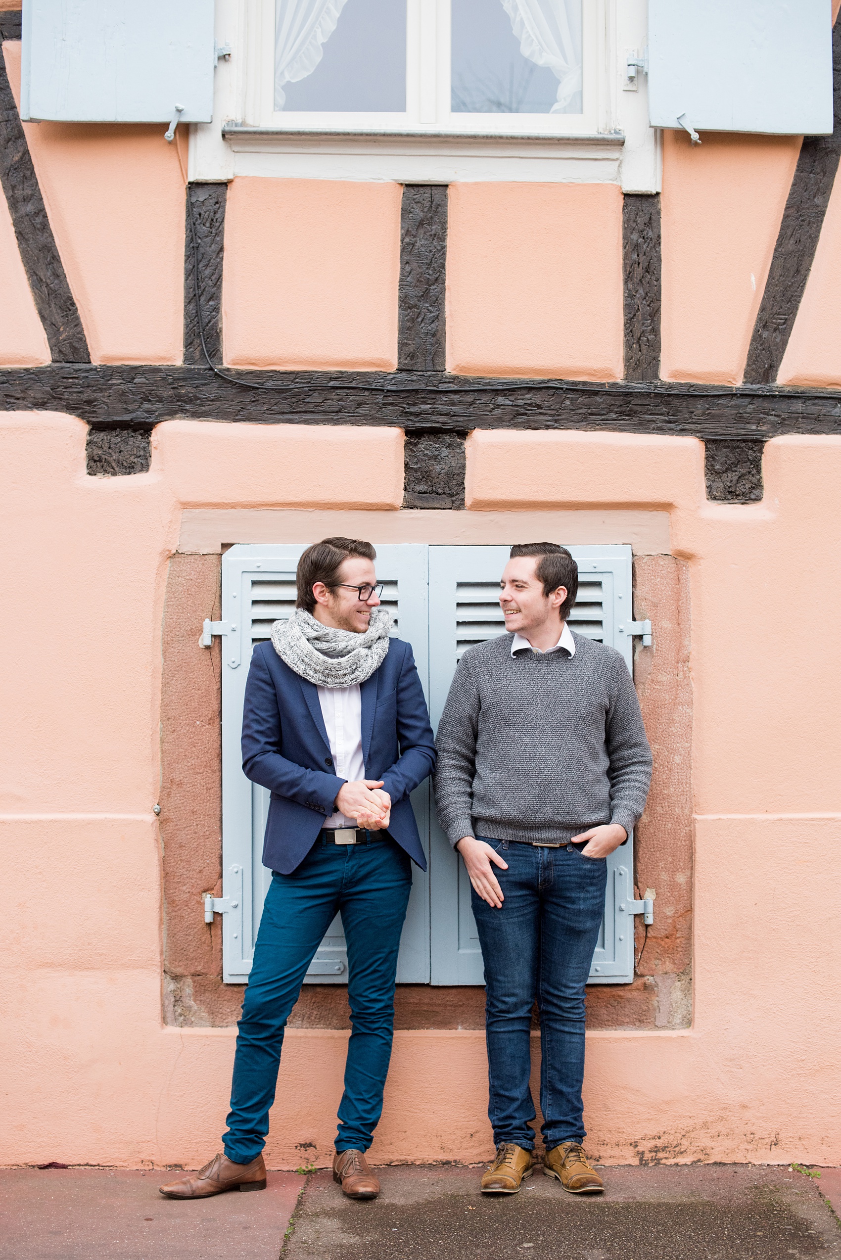 Mikkel Paige Photography pictures of an engagement session in Colmar, France in the Alsace region. Photo of the same sex gay couple with a colorful pink and blue building.