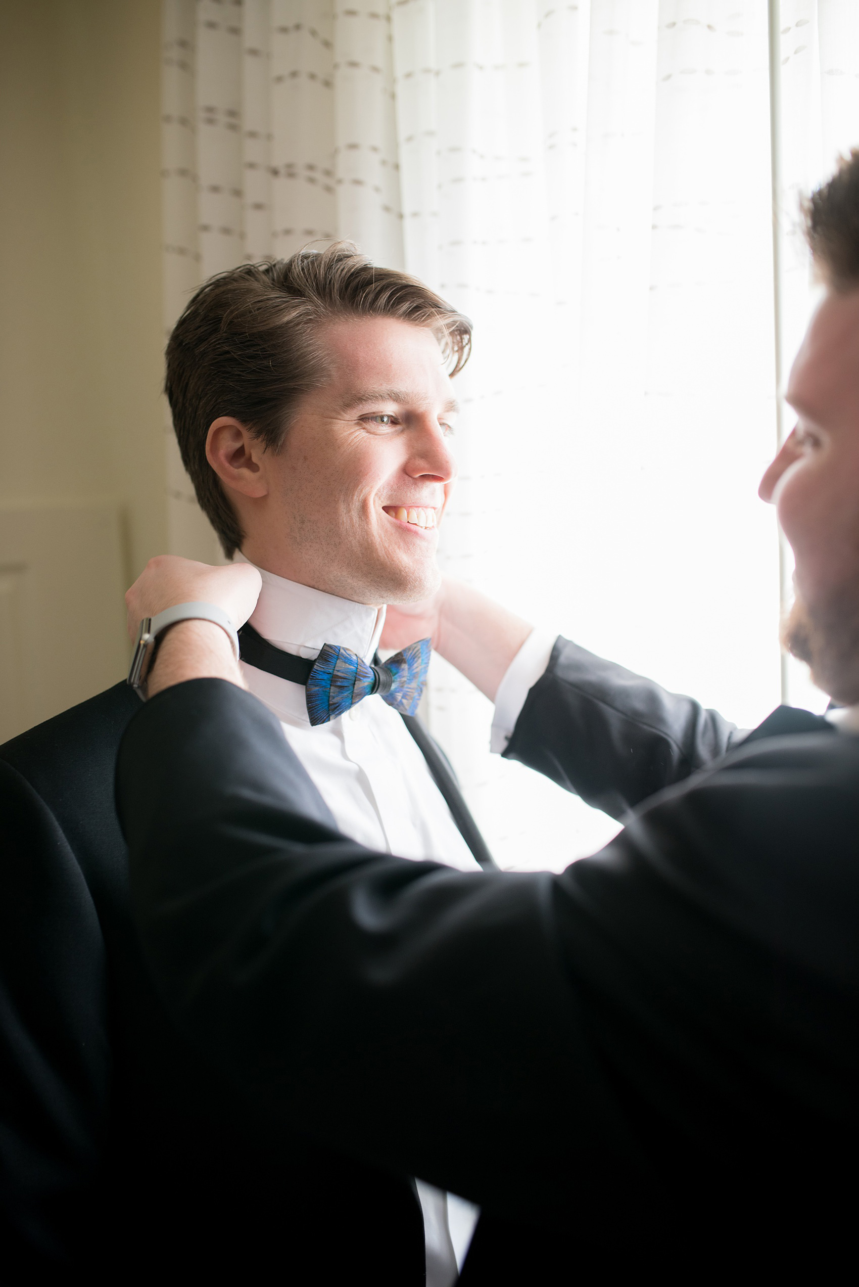 Mikkel Paige Photography photo of a wedding in Chapel Hill at Duke Chapel. A picture of the groom getting ready with his feather bow tie.