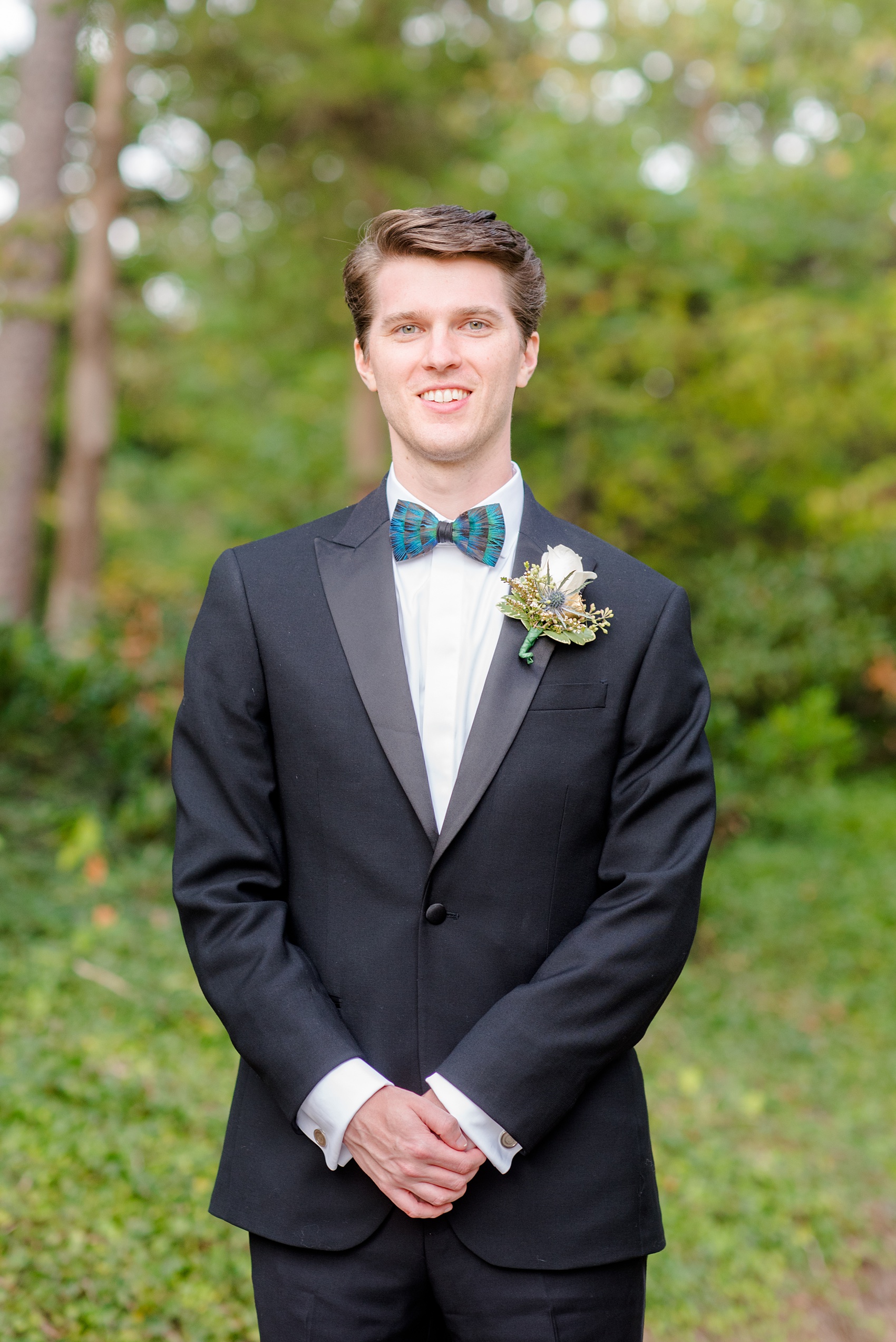 Mikkel Paige Photography photo of a wedding in Chapel Hill at Duke Chapel. Bride and groom with the gothic architecture. A picture of the groom in The Black Tux with white rose boutonniere and blue feather bow tie.