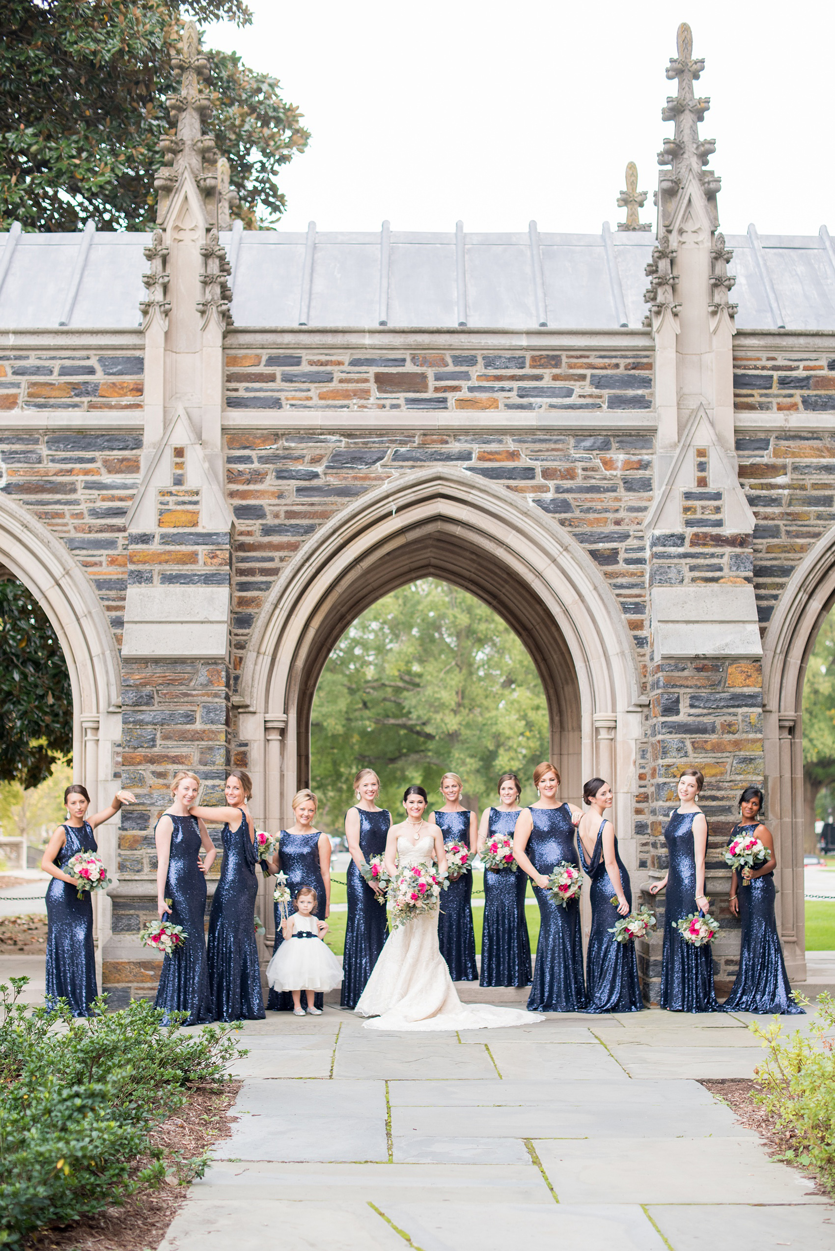 Mikkel Paige Photography photo of a wedding in Chapel Hill at Duke Chapel. Vogue like picture of the bridal party in blue sequin, low back gowns with the gothic architecture of the church.