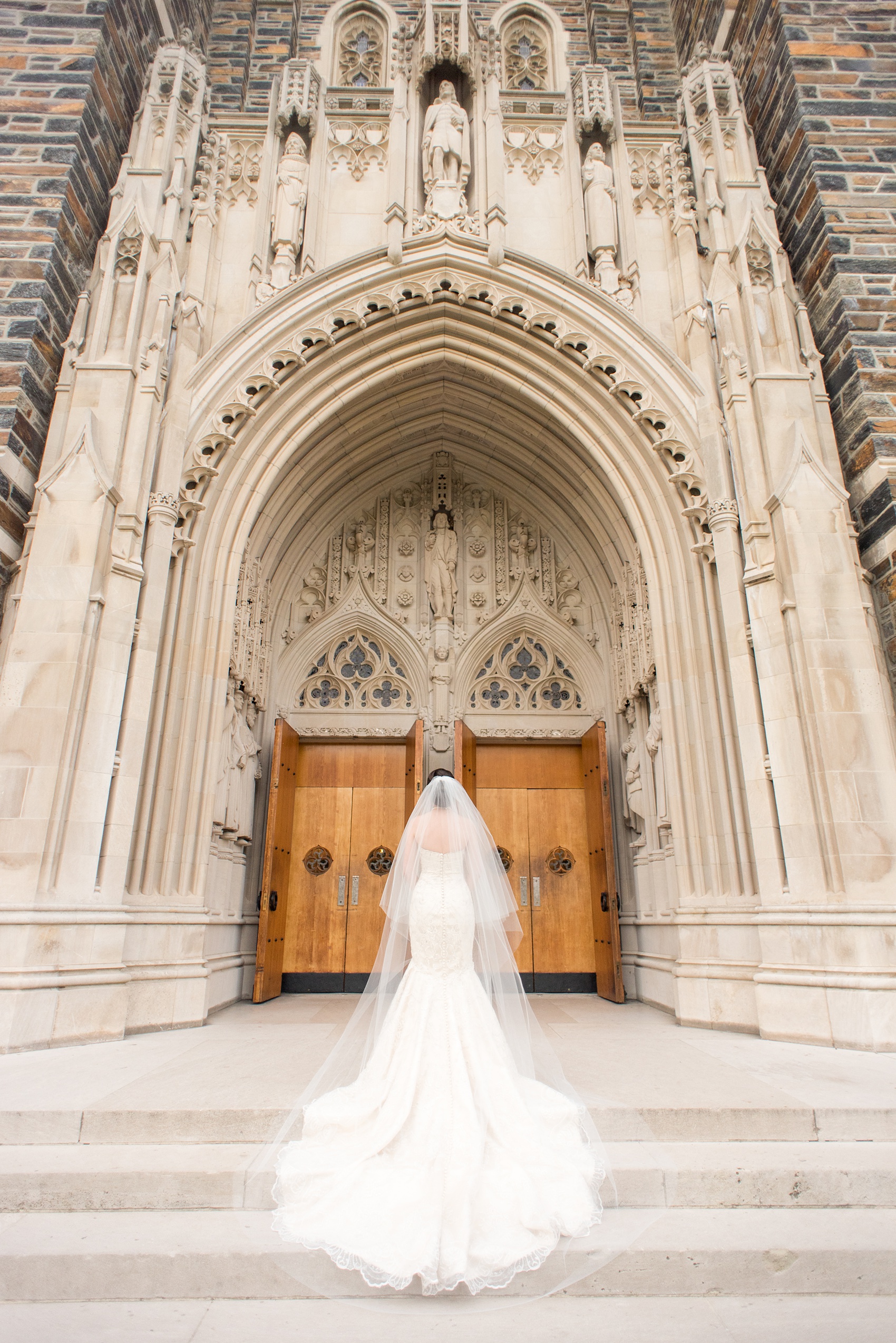 Mikkel Paige Photography photo of a wedding in Chapel Hill at Duke Chapel. Bride and groom with the gothic architecture. A portrait picture of the bride in front of the gothic church with her tulle veil.