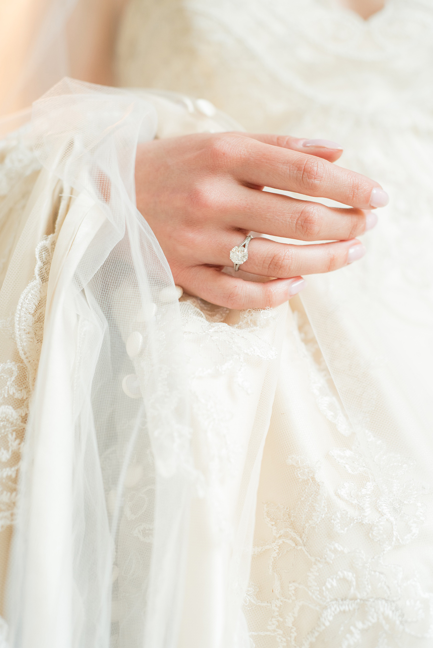 Mikkel Paige Photography photo of a wedding in Chapel Hill at Duke Chapel. Bride and groom with the gothic architecture. A portrait picture of the bride holding her tulle veil and off white gown, with her vintage engagement ring on her finger.