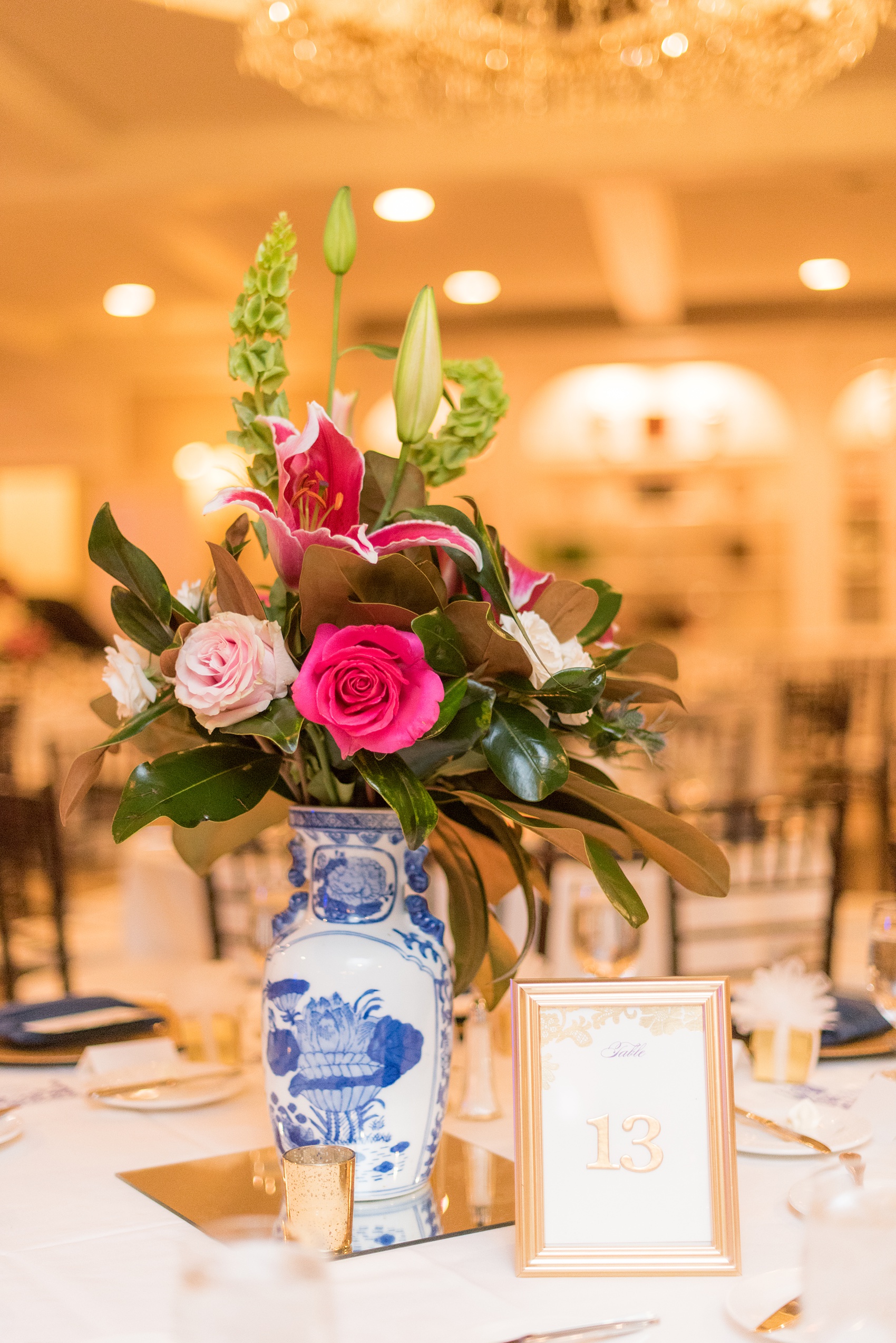 Mikkel Paige Photography photo of a wedding reception at Hope Valley Country Club in Chapel Hill, NC. Picture of the Delftware blue and white vase that held pink flowers, Bells of Ireland, and magnolia leaf centerpieces.