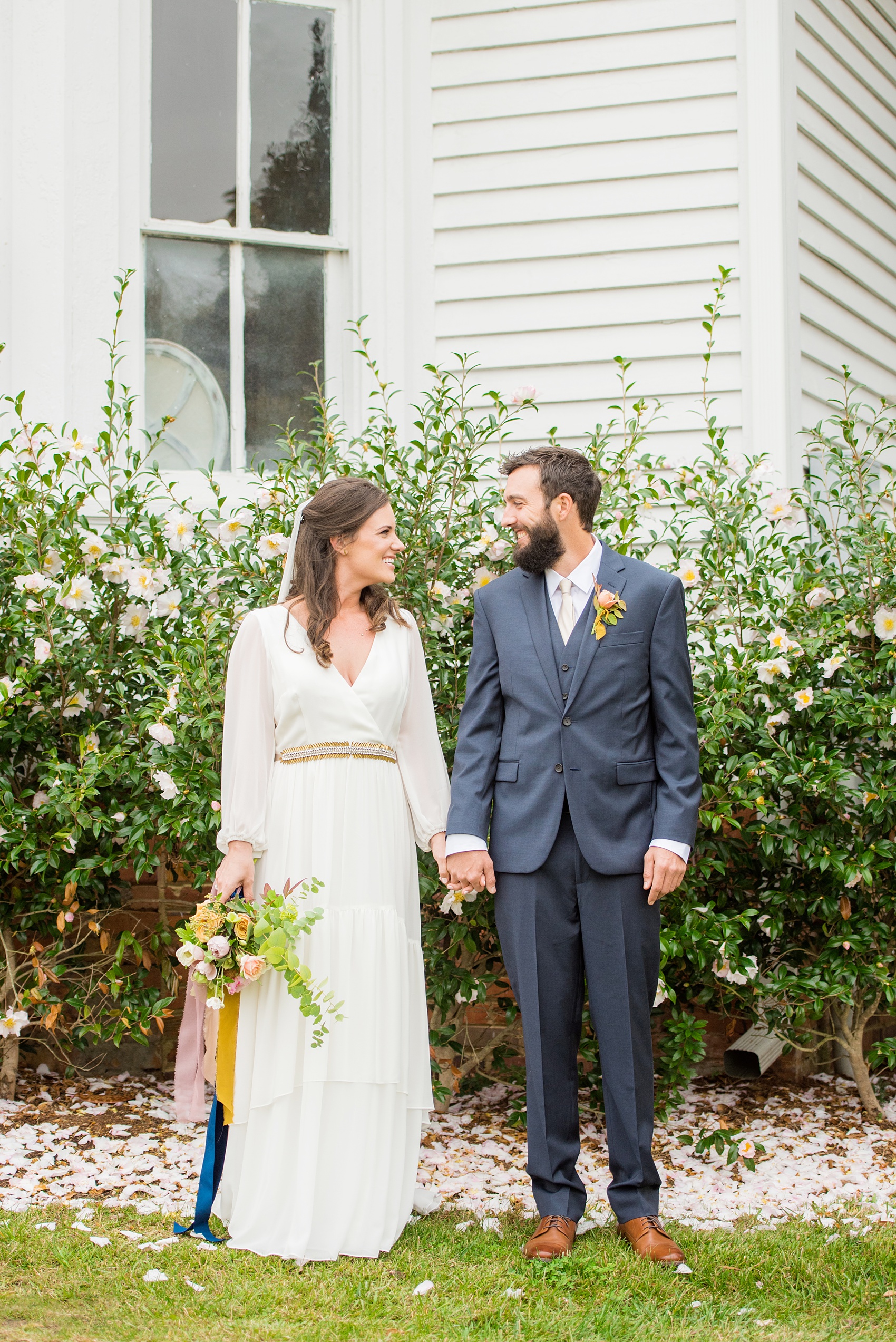 Mikkel Paige Photography photos from a wedding at Leslie-Alford Mims House in North Carolina. Picture of the bride and groom at the historic southern home venue amidst Camellia pink flower petals.