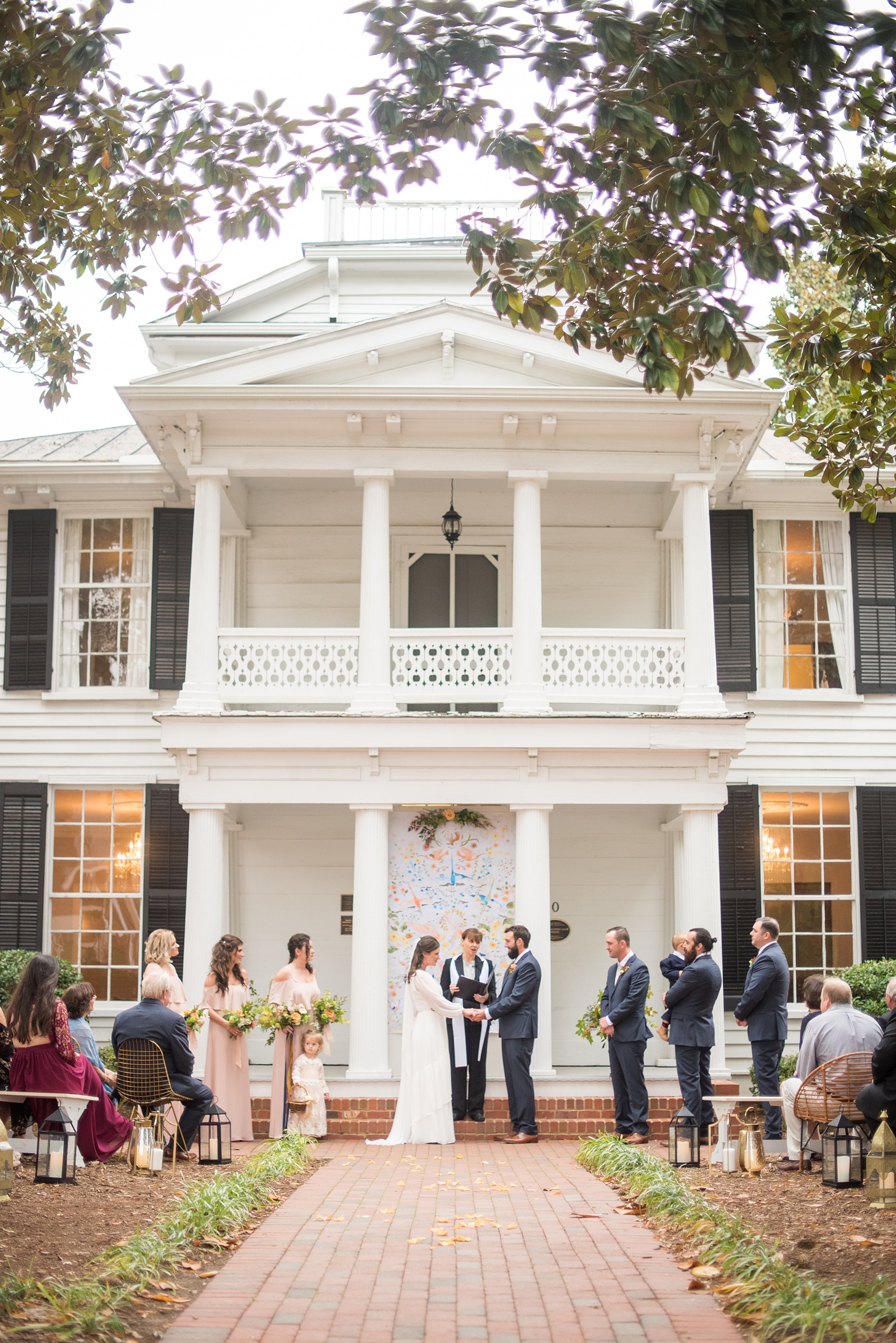 Mikkel Paige Photography photos from a wedding at Leslie-Alford Mims House in North Carolina. Picture of the outdoor ceremony with colorful BHLDN batik backdrop for nuptials at the historic southern home.