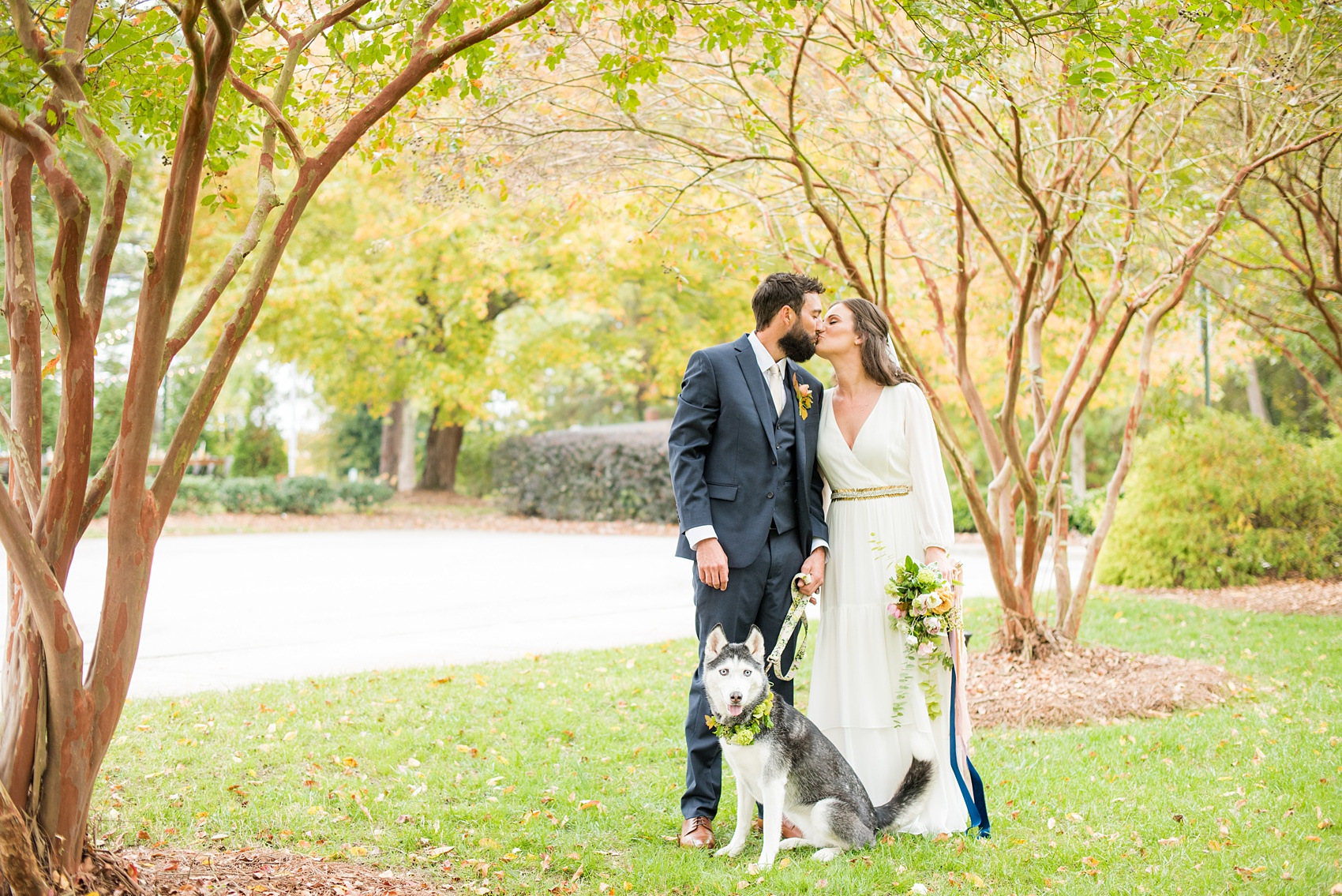 Mikkel Paige Photography photos from a wedding at Leslie-Alford Mims House in North Carolina. Picture of the Boho bride and groom with their Husky dog in a floral collar on their fall Mad Dash Weddings event day.