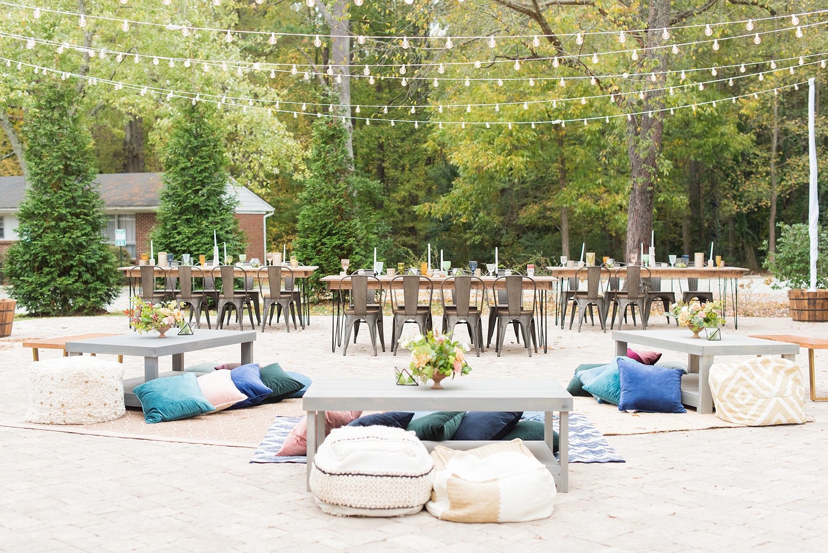 Mikkel Paige Photography photos from a wedding at Leslie-Alford Mims House in North Carolina. Picture of the outdoor reception setup with farm tables, metal chairs, rugs and pillow seating and market lights.