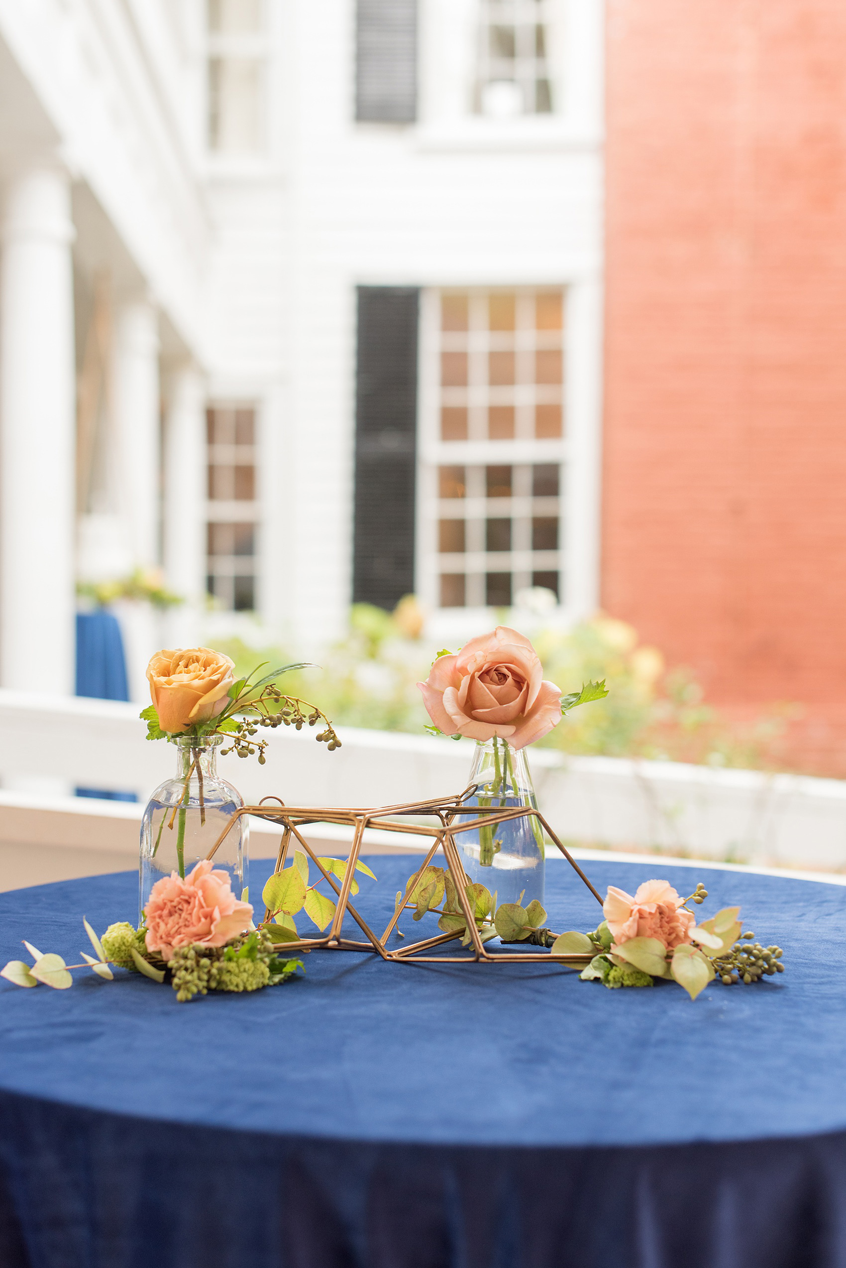 Mikkel Paige Photography photos from a wedding at Leslie-Alford Mims House in North Carolina. Picture of a blue velvet cocktail table with gold metal geometric shapes and colorful fall flowers.