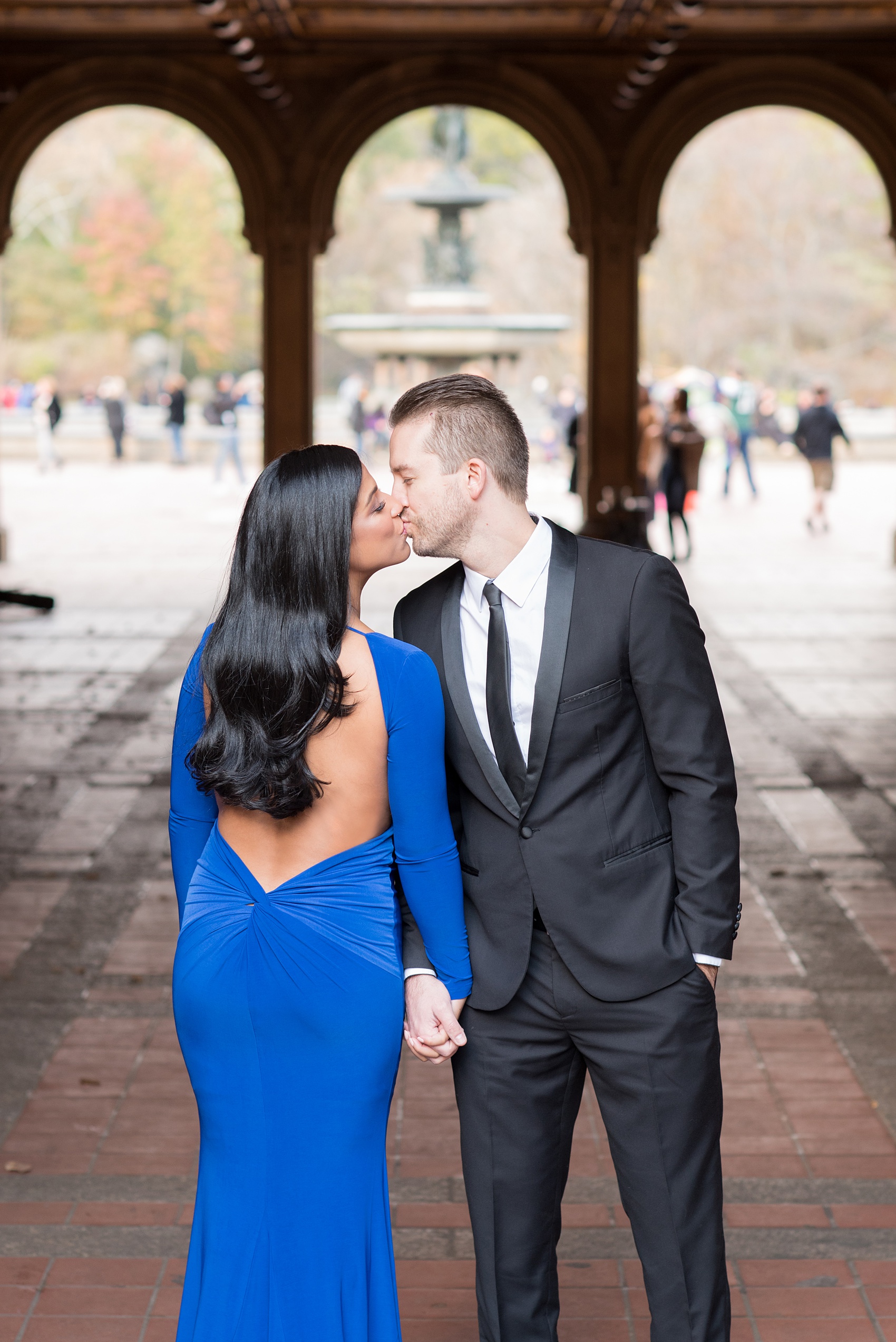 Mikkel Paige Photography pictures of an engagement session in Central Park. The bride wore a sexy back cobalt blue dress for a kiss by Bethesda Fountain.