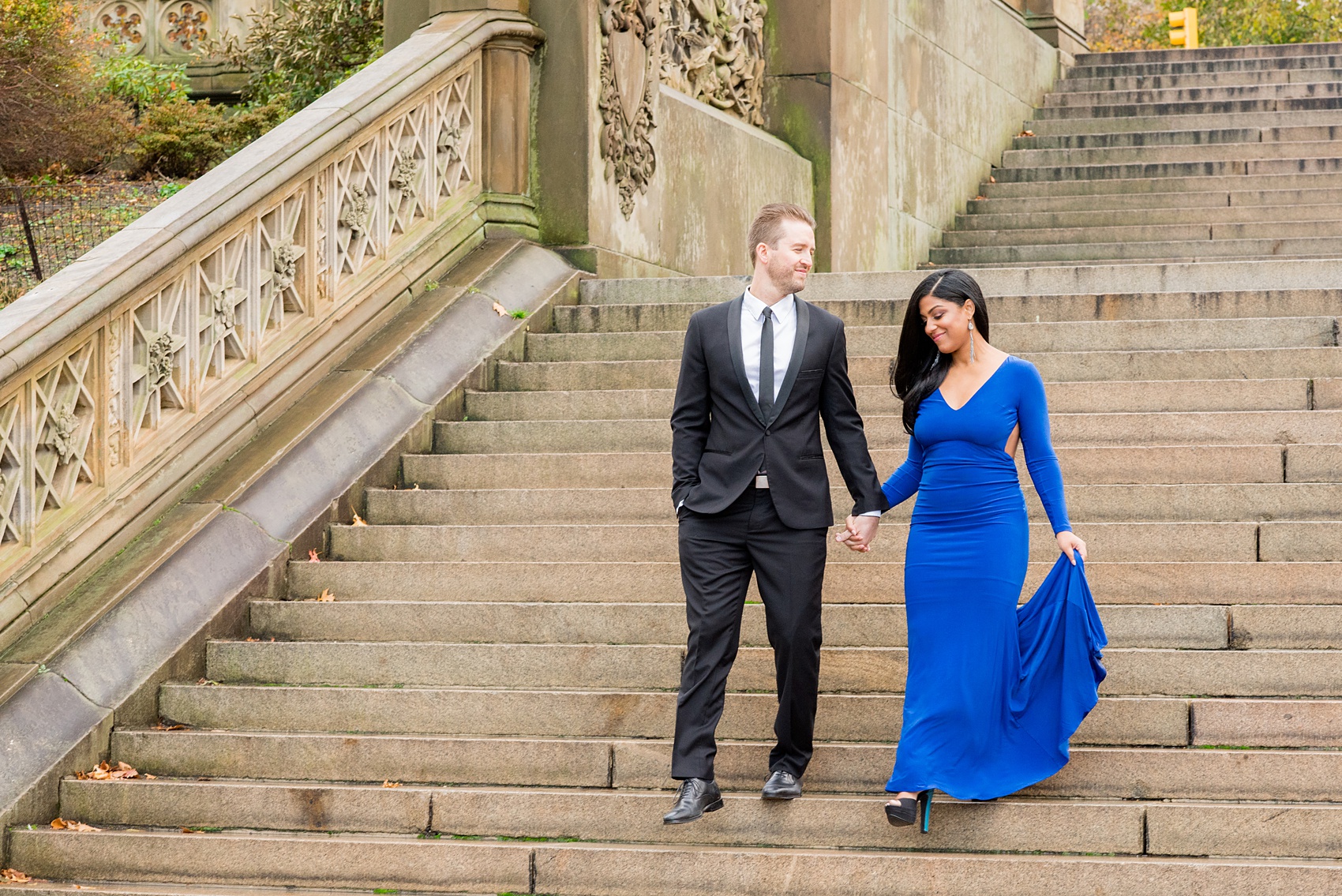 Mikkel Paige Photography pictures of an engagement session in Central Park. A photo of the bride and groom walking down the stairs of Bethesda Terrace.