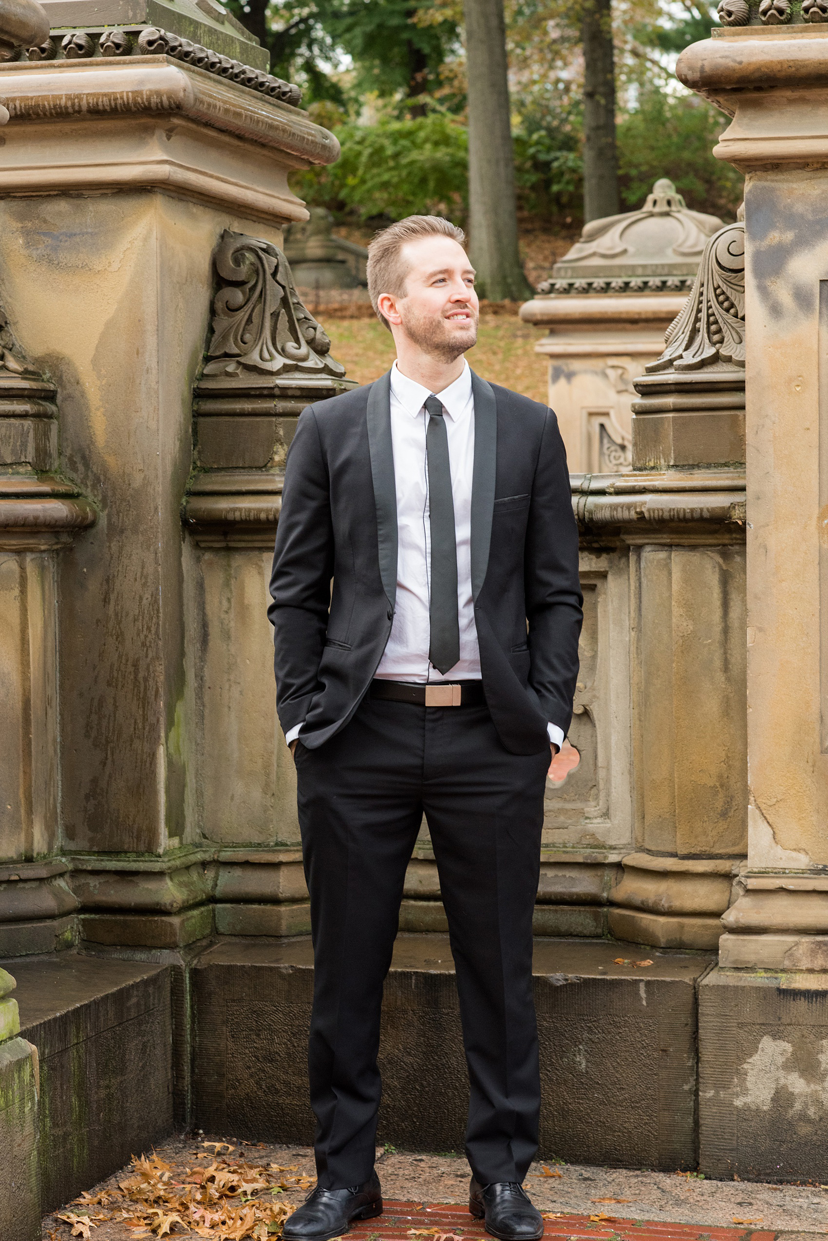 Mikkel Paige Photography pictures of an engagement session in Central Park. A photo of the groom in a sleek, modern suit by Bethesda Fountain.