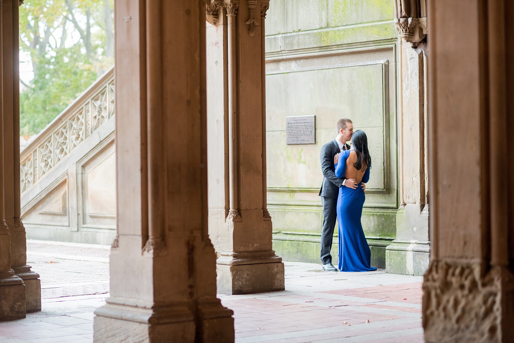 Mikkel Paige Photography pictures of an engagement session in Central Park. A photo of the bride and groom hugging at Bethesda Terrace.