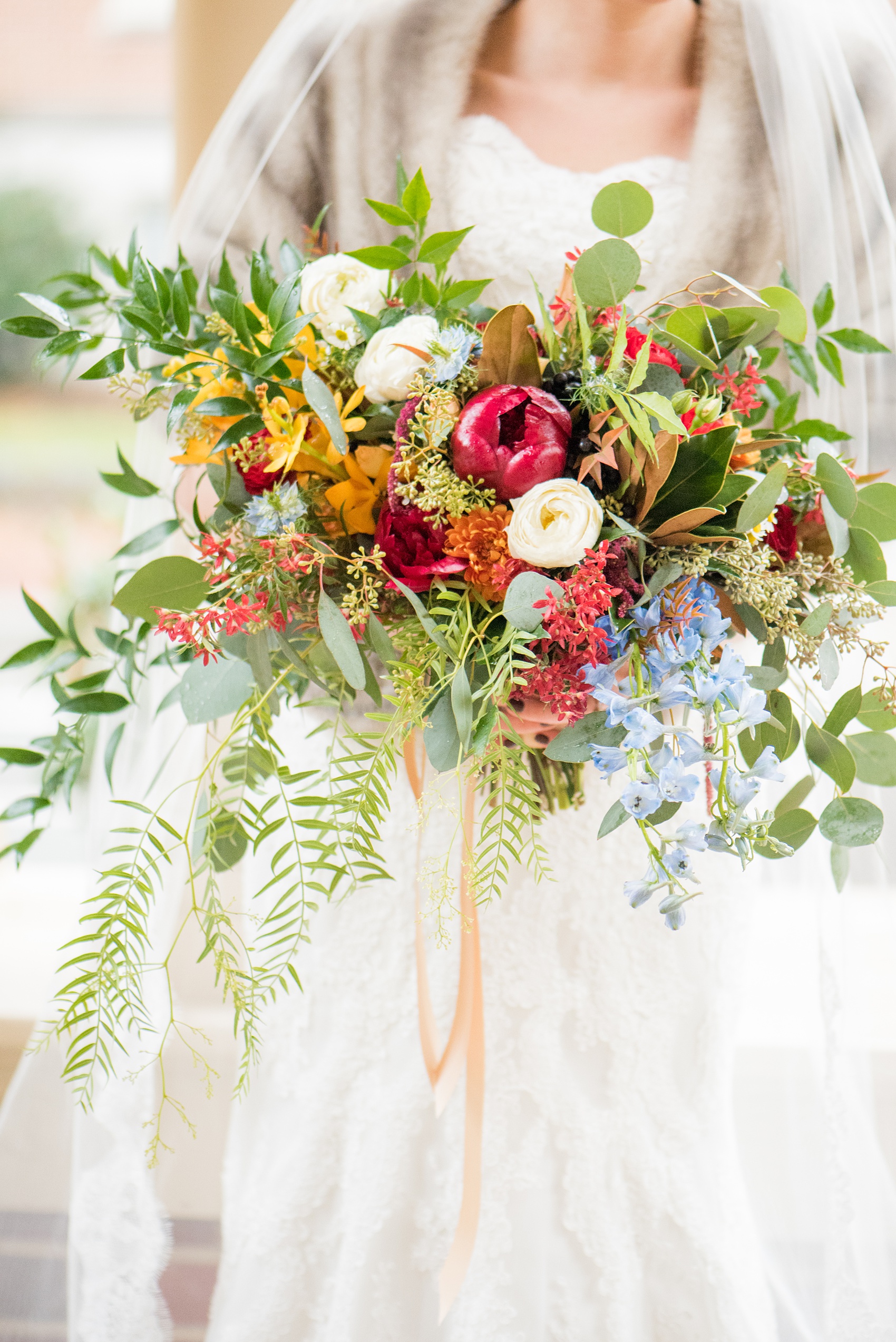 Mikkel Paige Photography photos at The Carolina Inn for a warm and colorful winter wedding. Detail picture of the bride's red, orange, and white seasonal bouquet for her snowy day in Chapel Hill, NC. 