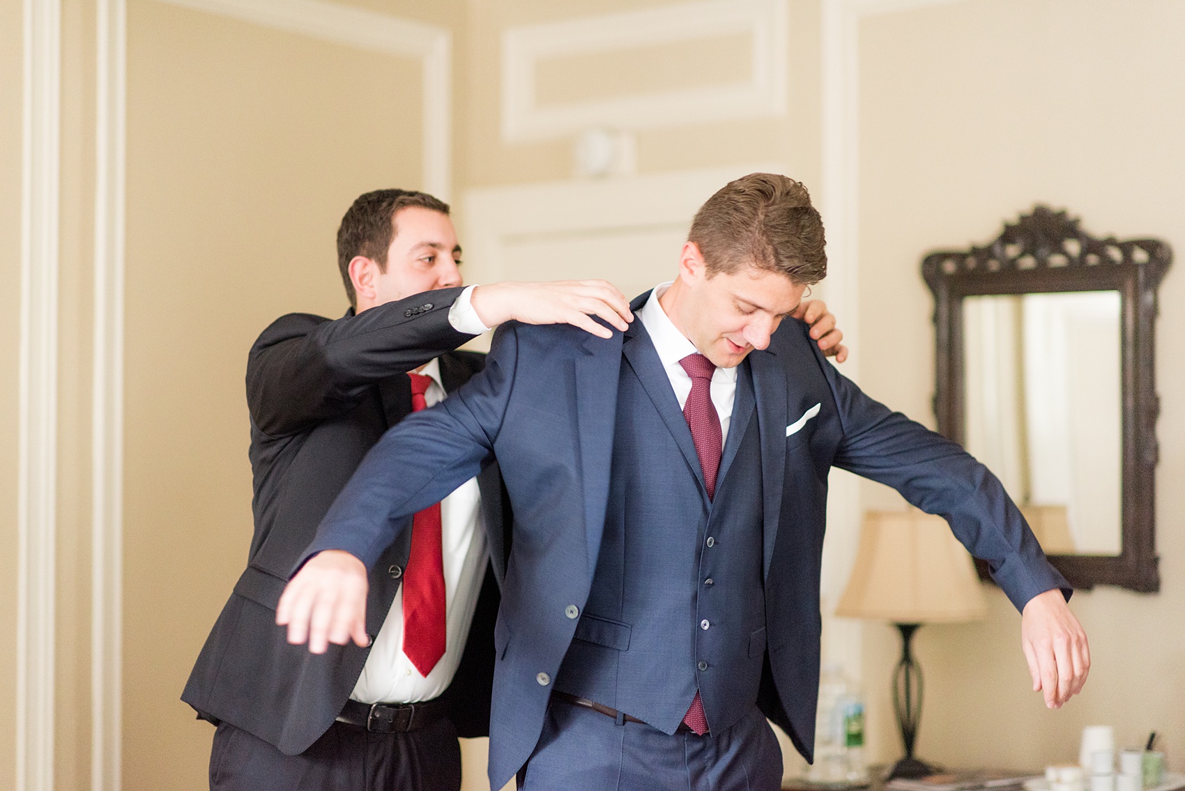 Mikkel Paige Photography photos of a wedding at Crabtree's Kittle House in Chappaqua, New York. Picture of the groom getting ready with his family in his navy linen double breasted suit.