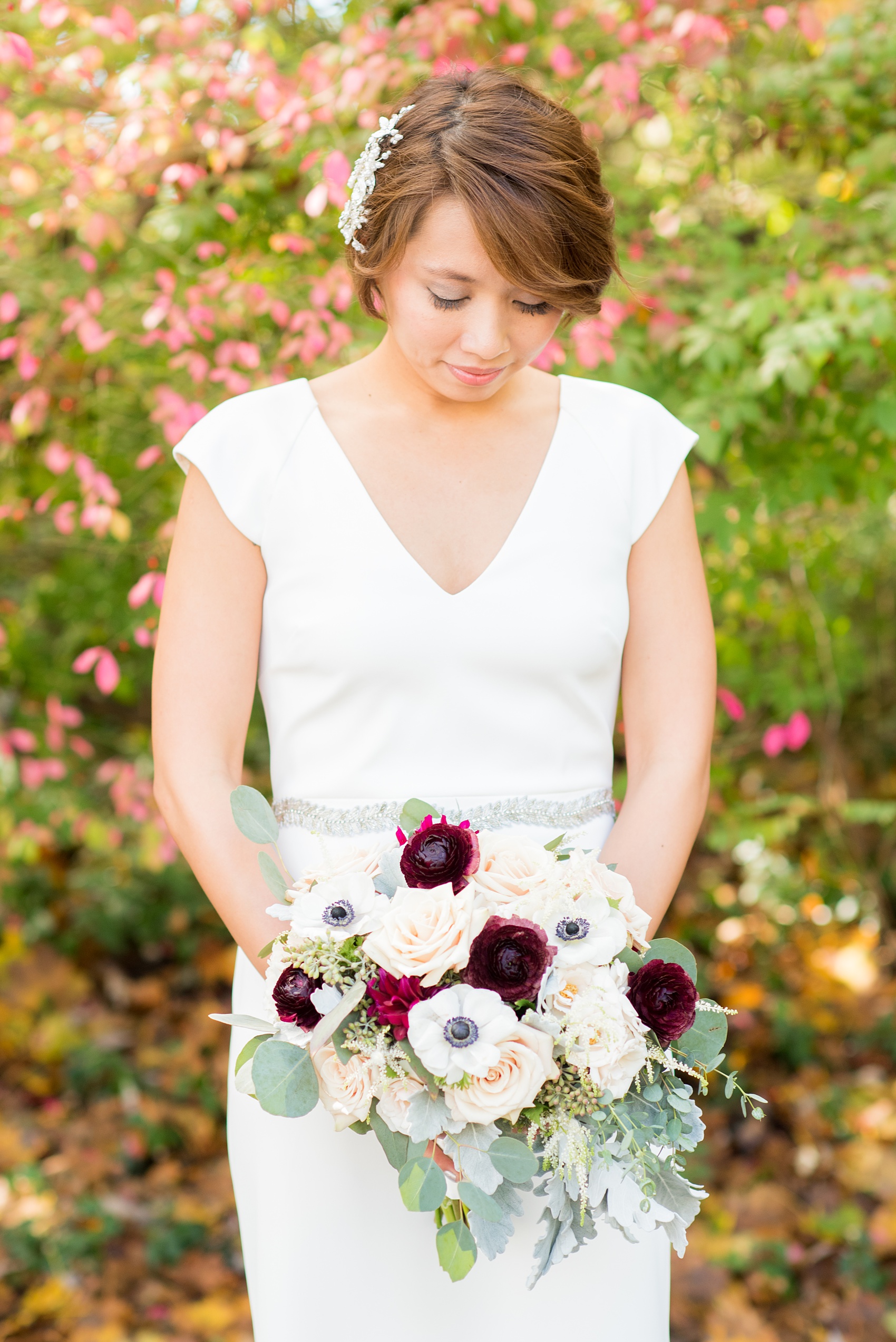 Mikkel Paige Photography photos of a wedding at Crabtree's Kittle House in Chappaqua, New York. Picture of the bride in her short sleeve BHLDN gown with fall foliage behind her.