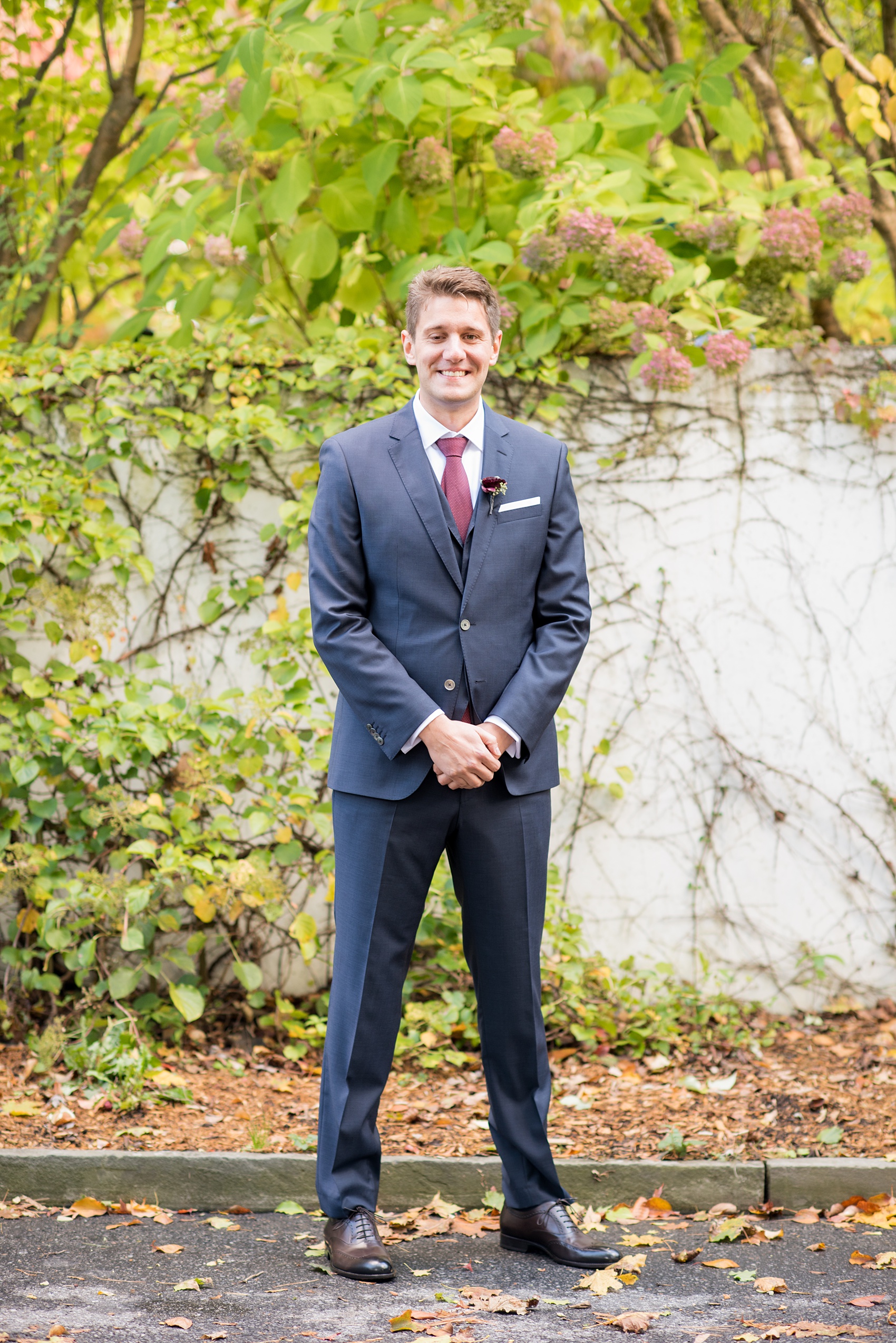 Mikkel Paige Photography photos of a wedding at Crabtree's Kittle House in Chappaqua, New York. Picture of the groom in a navy blue linen double breasted suit with fall dark red tie.
