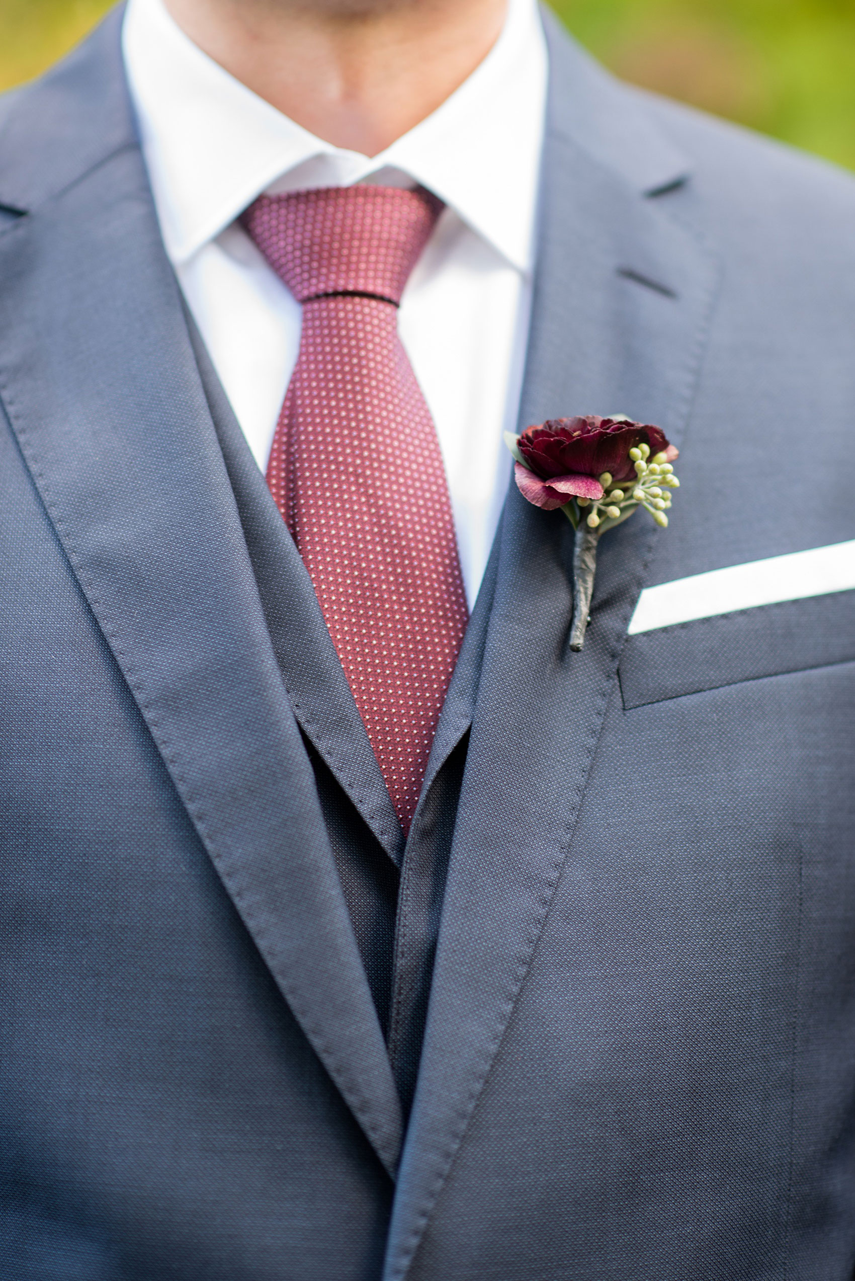 Mikkel Paige Photography photos of a wedding at Crabtree's Kittle House in Chappaqua, New York. Picture of the groom's navy blue linen double breasted suit with fall dark red boutonniere.